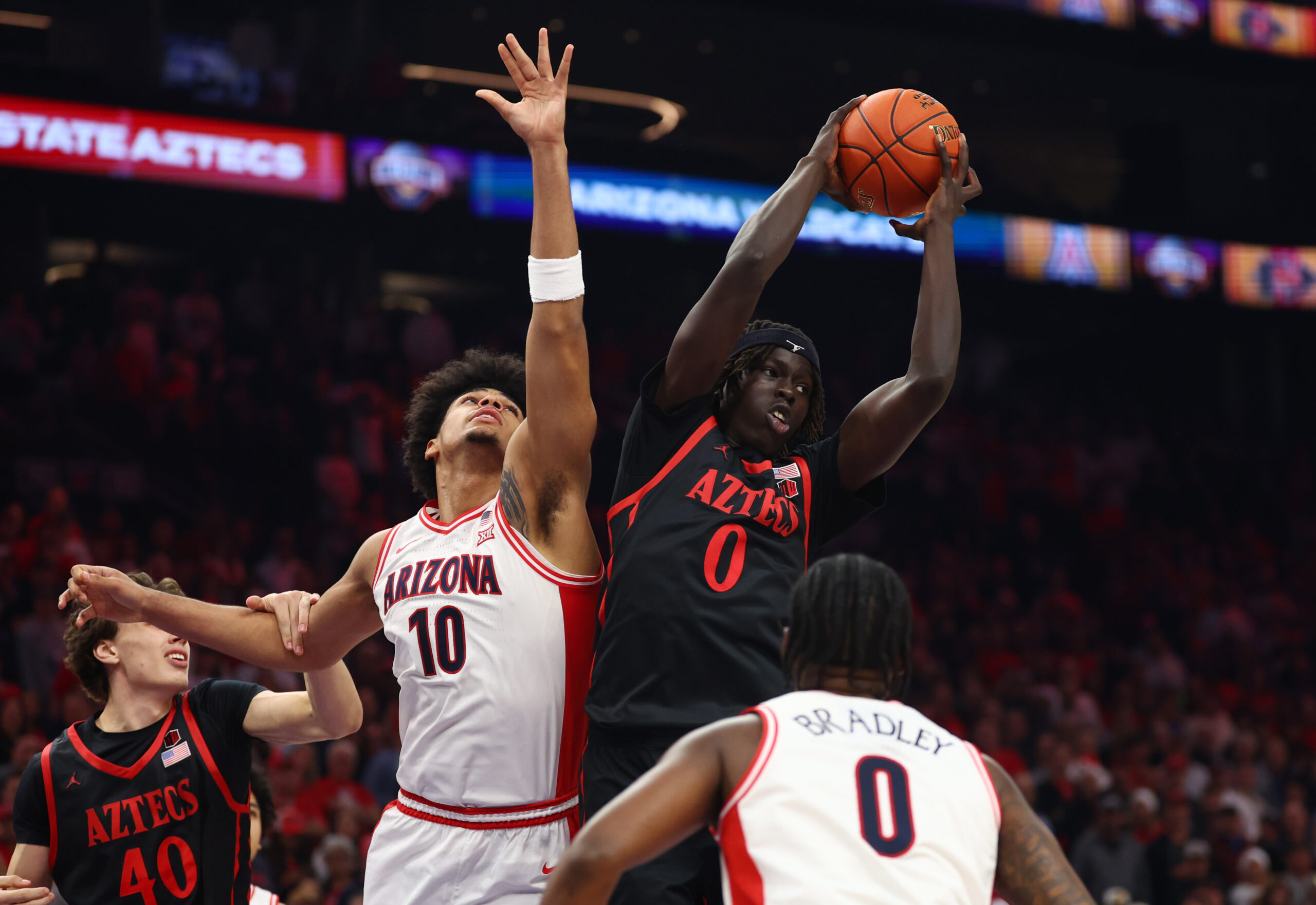 Dec 20, 2025; Phoenix, Arizona, USA; San Diego State Aztecs forward Magoon Gwath (0) grabs a rebound against Arizona Wildcats forward Koa Peat (10) during the Hall of Fame Series at Mortgage Matchup Center. Mandatory Credit: Mark J. Rebilas-Imagn Images