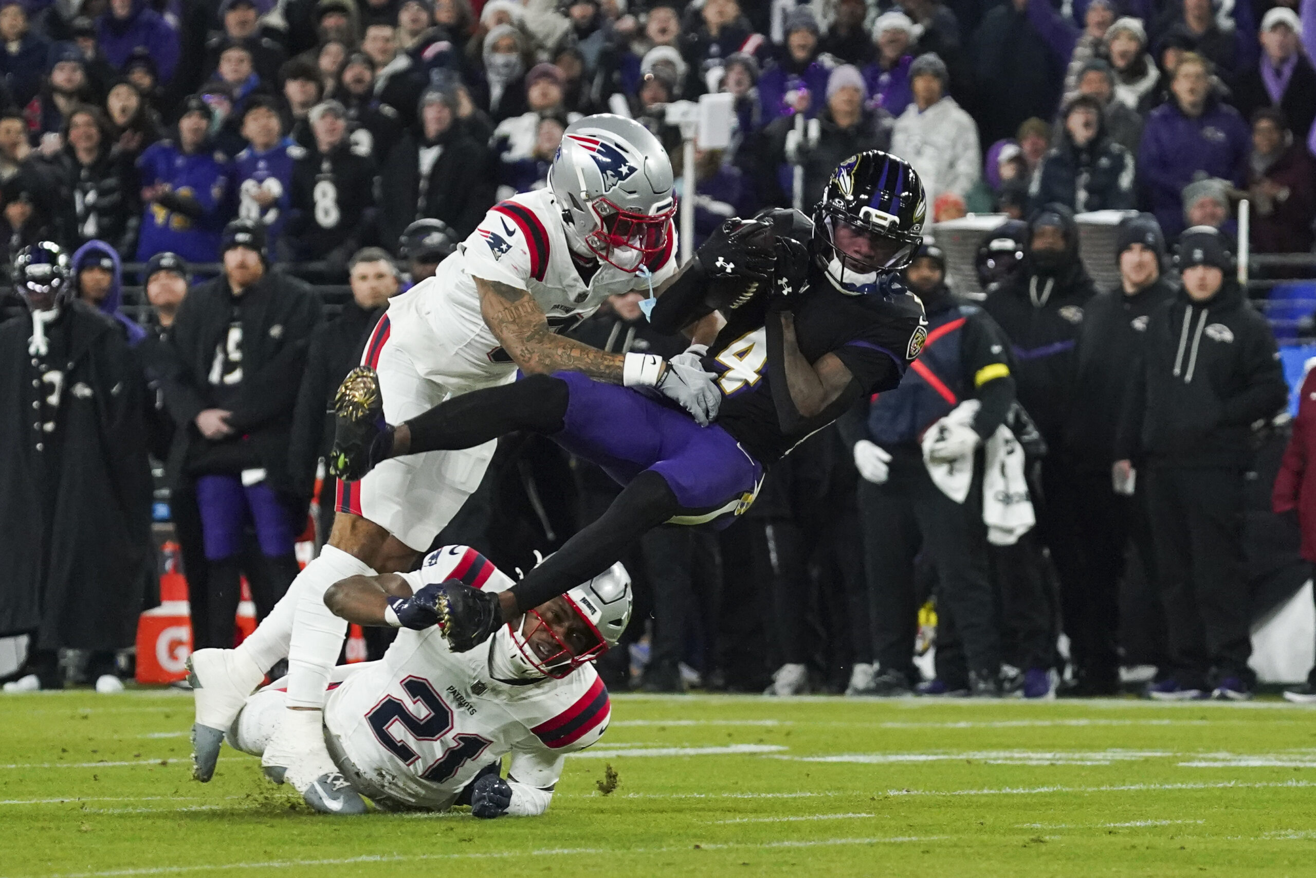 Dec 21, 2025; Baltimore, Maryland, USA;  Baltimore Ravens wide receiver Zay Flowers (4) is hit by New England Patriots cornerback Christian Gonzalez (0) during the first quarter of the game at M&T Bank Stadium. Mandatory Credit: James Lang-Imagn Images