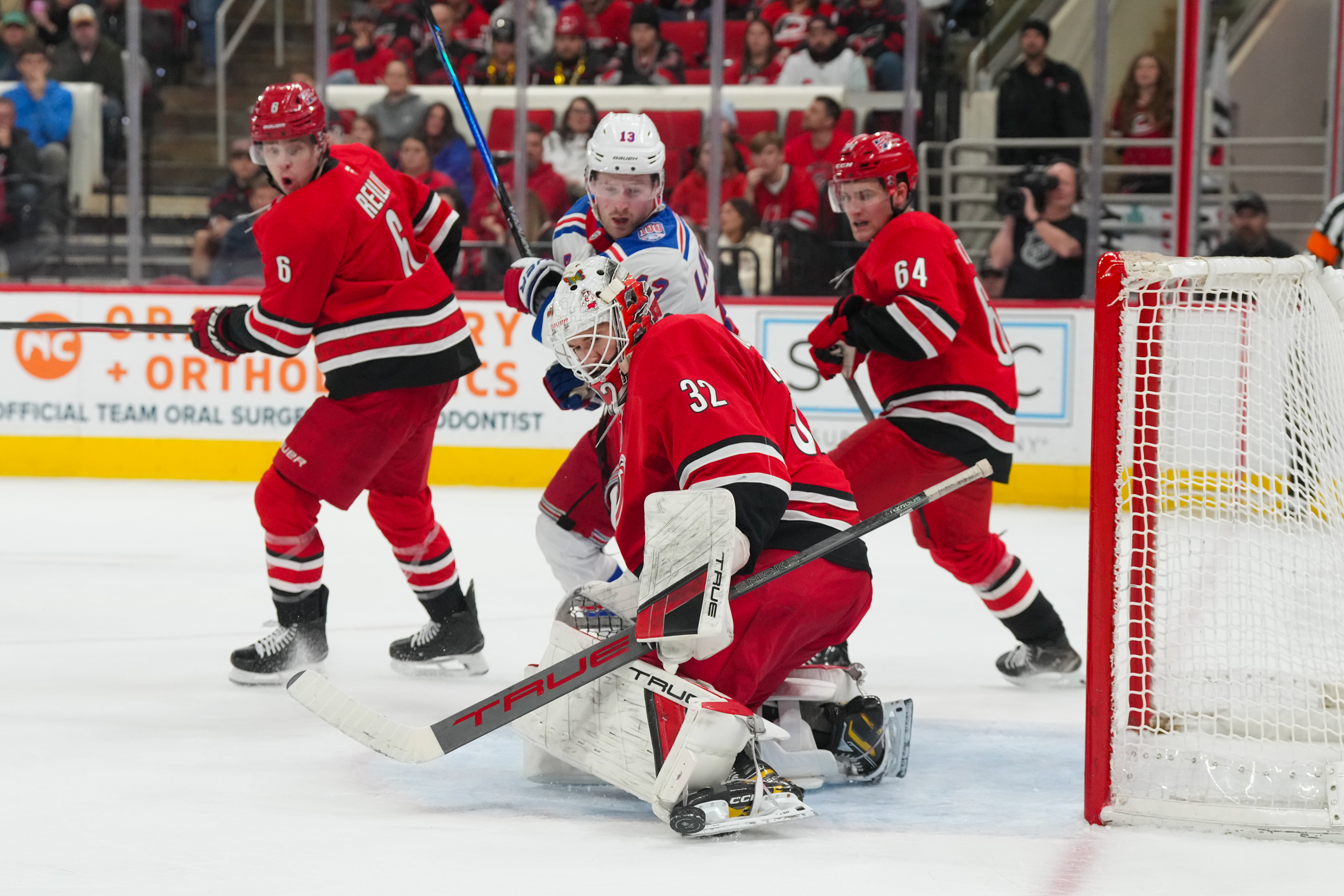 Dec 29, 2025; Raleigh, North Carolina, USA;  Carolina Hurricanes goaltender Brandon Bussi (32) stops the shot next to New York Rangers left wing Alexis Lafreniere (13) during the second period at Lenovo Center. Mandatory Credit: James Guillory-Imagn Images