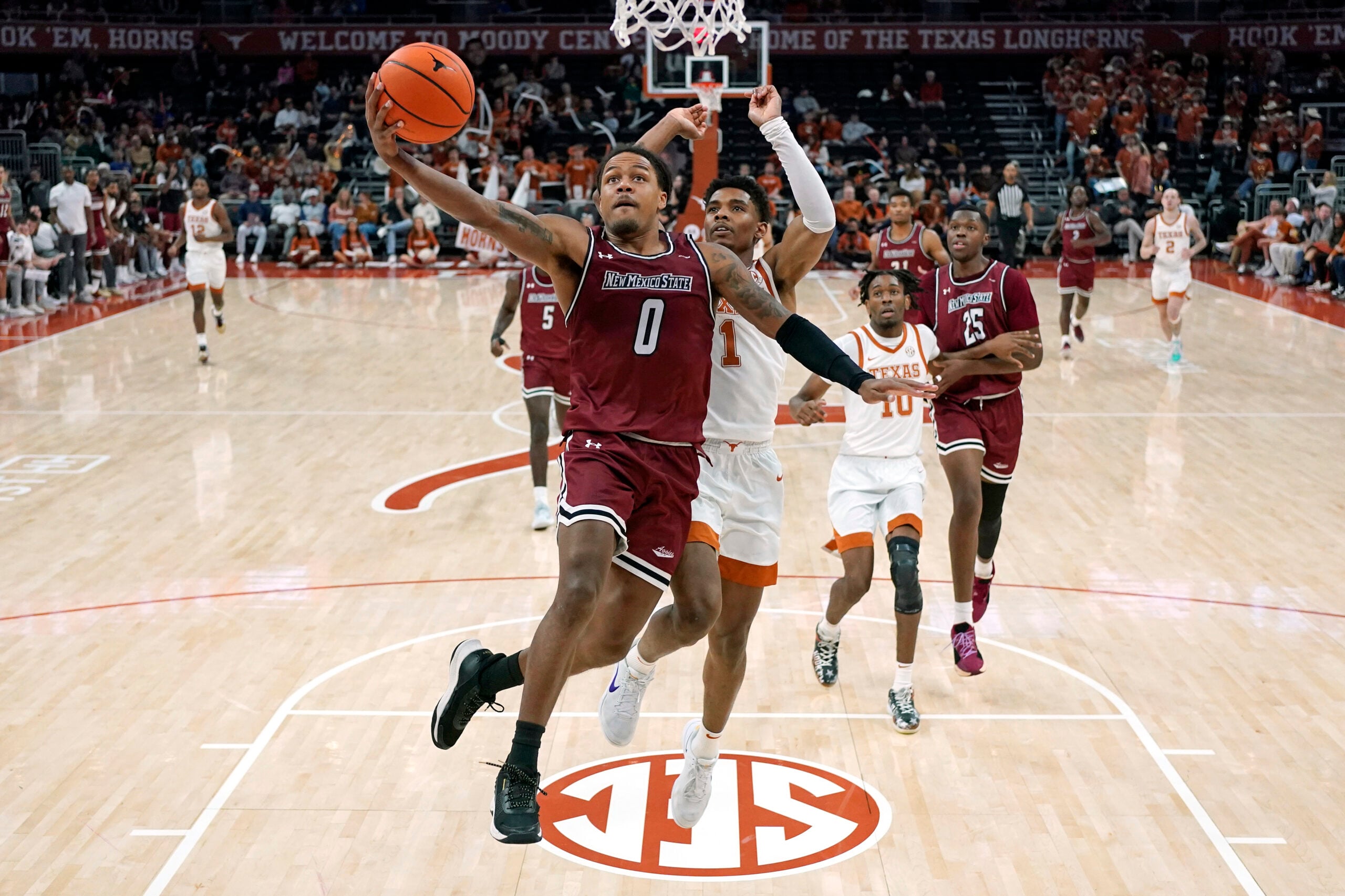 Dec 12, 2024; Austin, Texas, USA; New Mexico State Aggies guard Dionte Bostick (0) drives to the basket past Texas Longhorns guard Julian Larry (1) during the first half at Moody Center. Mandatory Credit: Scott Wachter-Imagn Images