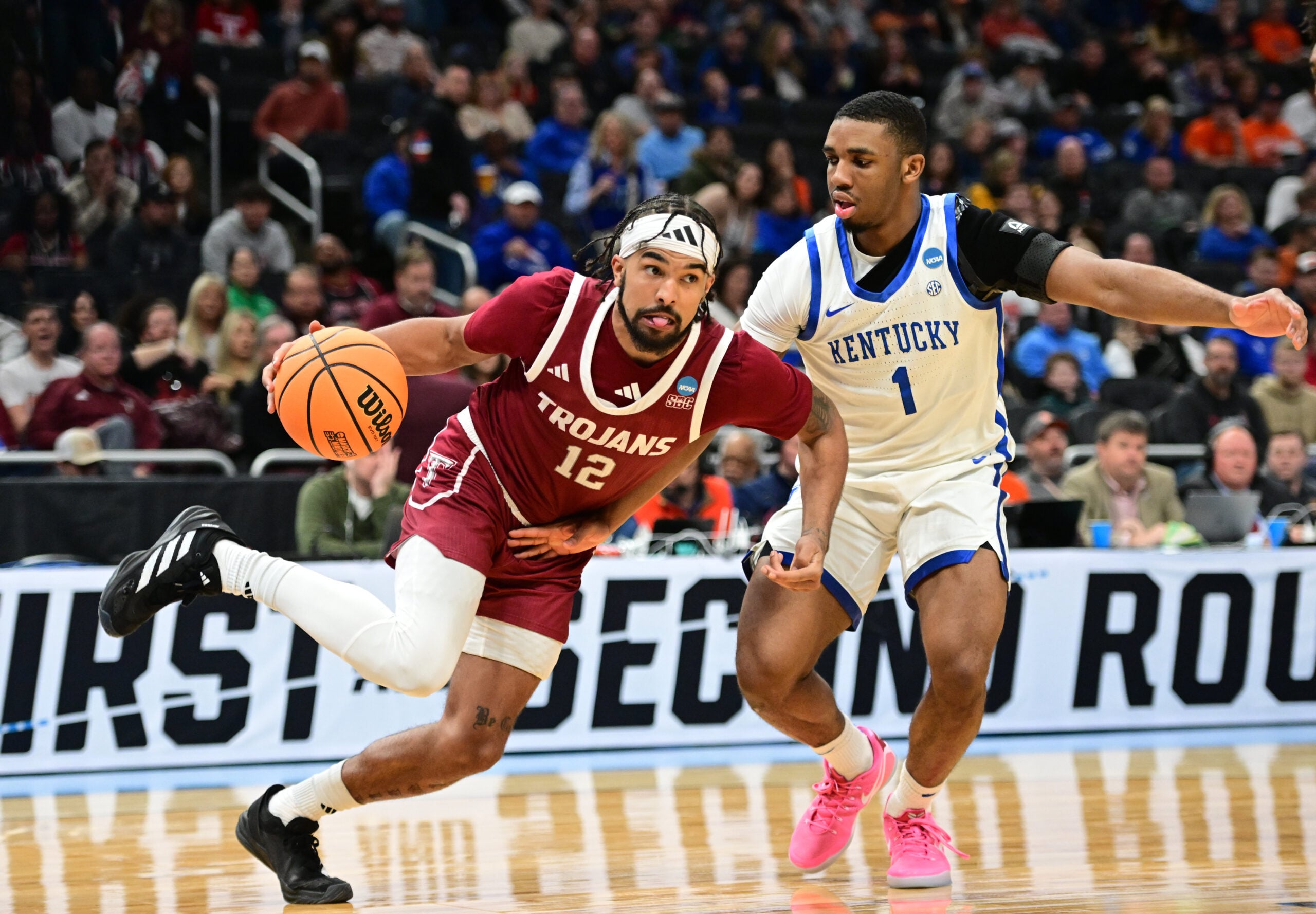 Mar 21, 2025; Milwaukee, WI, USA; Troy Trojans guard Tayton Conerway (12) drives to the hoop past Kentucky Wildcats guard Lamont Butler (1) during the second half at Fiserv Forum. Mandatory Credit: Benny Sieu-Imagn Images