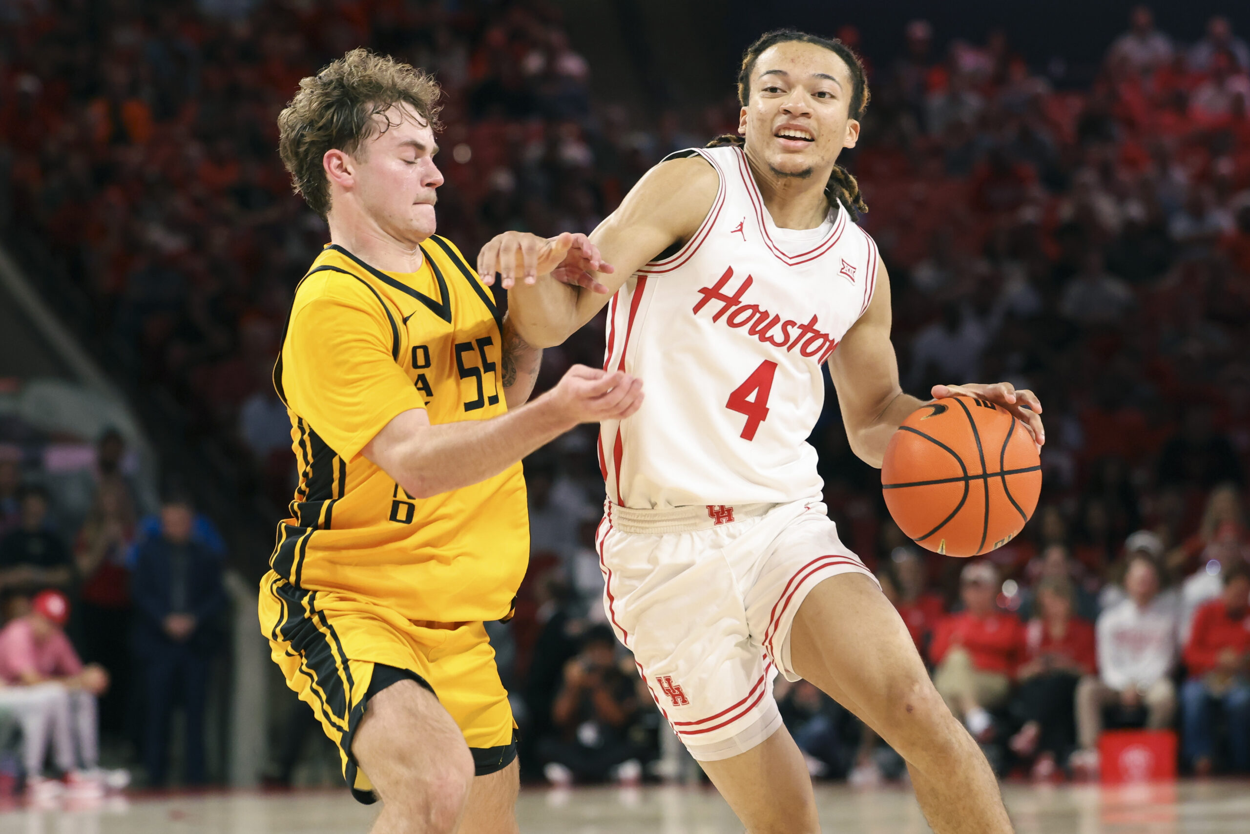 Nov 12, 2025; Houston, Texas, USA; Houston Cougars guard Kingston Flemings (4) drives with the ball as Oakland Golden Grizzlies guard Brody Robinson (55) defends during the first half at Fertitta Center. Mandatory Credit: Troy Taormina-Imagn Images