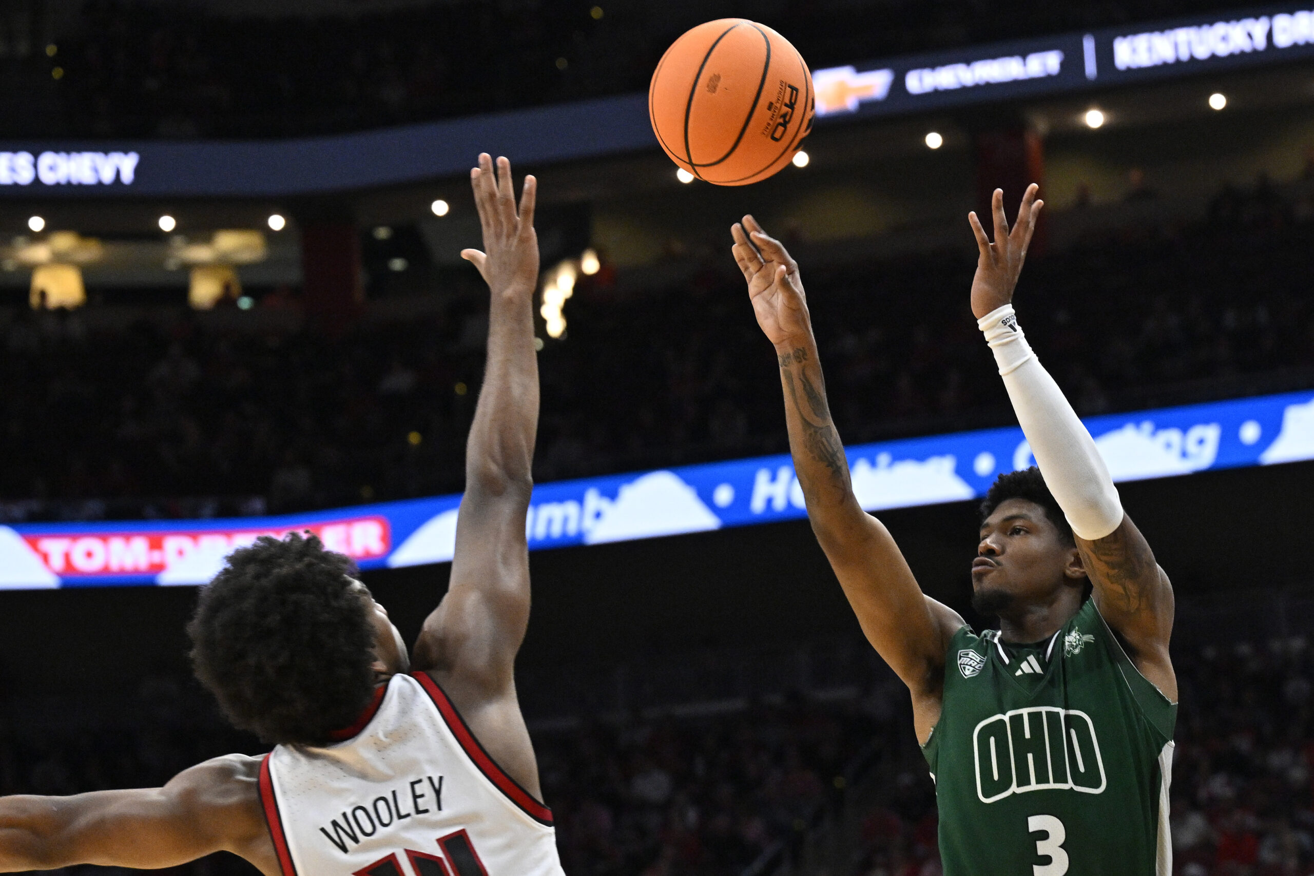 Nov 15, 2025; Louisville, Kentucky, USA;  Ohio Bobcats guard Dior Conners (3) shoots against Louisville Cardinals guard Adrian Wooley (14) during the first half at KFC Yum! Center. Mandatory Credit: Jamie Rhodes-Imagn Images