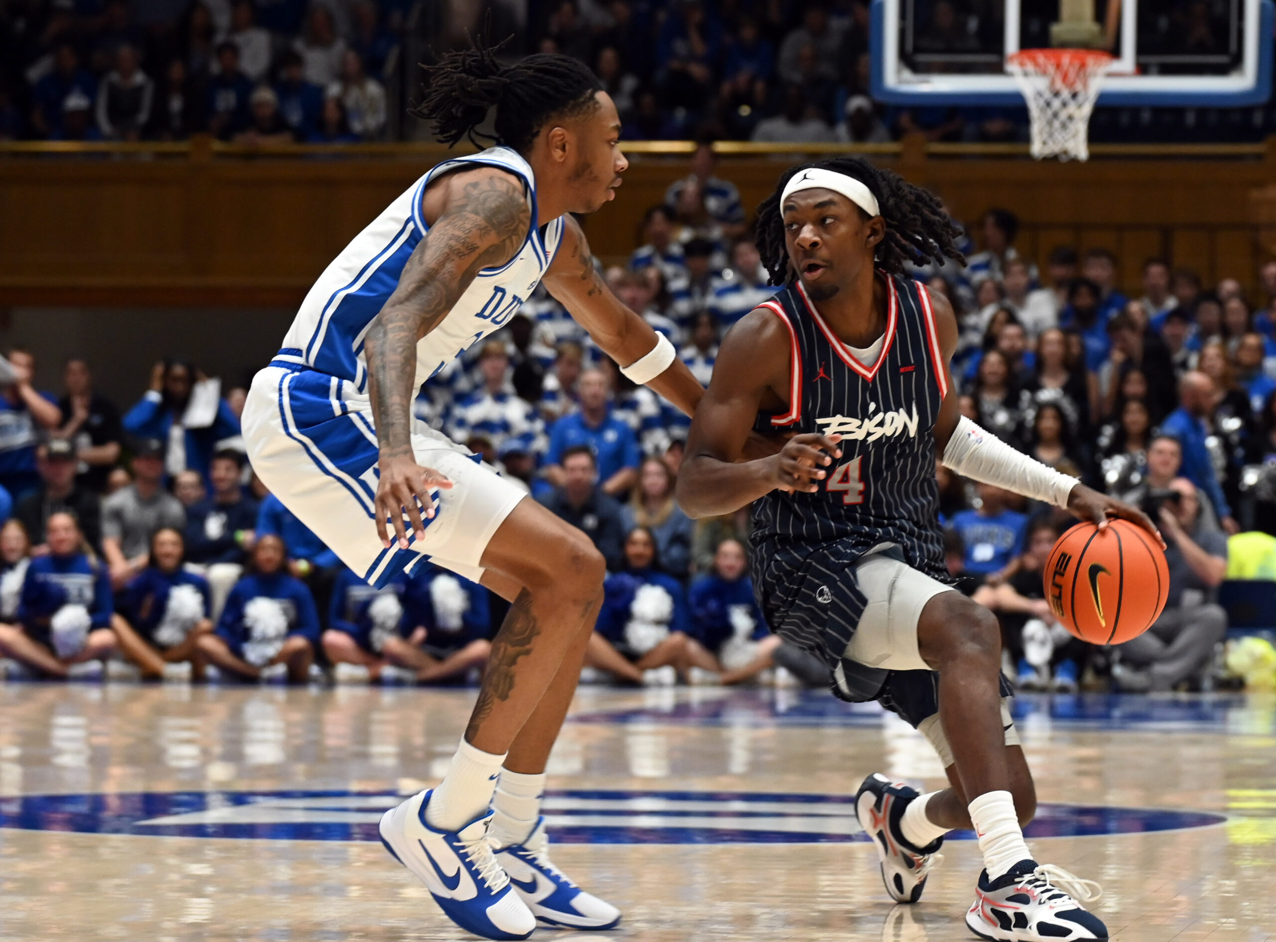 Nov 23, 2025; Durham, North Carolina, USA; Howard Bison guard Alex Cotton (4) controls the ball in front of Duke Blue Devils forward Isaiah Evans (3) during the first half at Cameron Indoor Stadium. Mandatory Credit: Rob Kinnan-Imagn Images