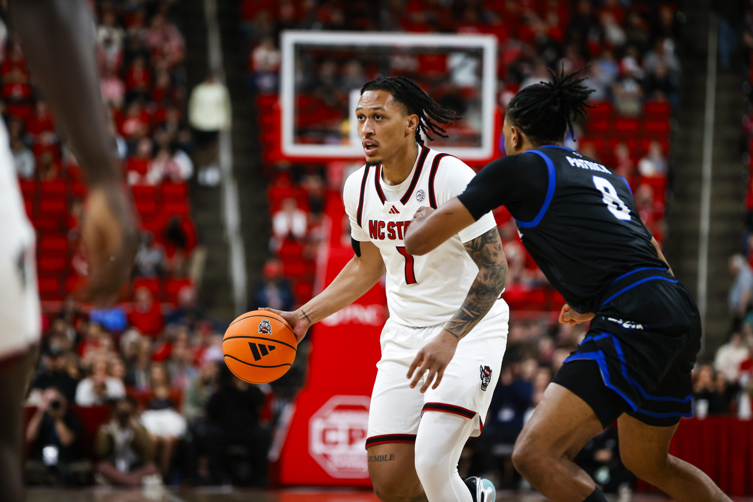 dDec 6, 2025; Raleigh, North Carolina, USA;  NC State Wolfpack forward Darrion Williams (1) dribbles the ball as UNC Asheville Bulldogs guard DJ Patrick (8) defends during the first half of the game at Lenovo Center. Mandatory Credit: Jaylynn Nash-Imagn Images
