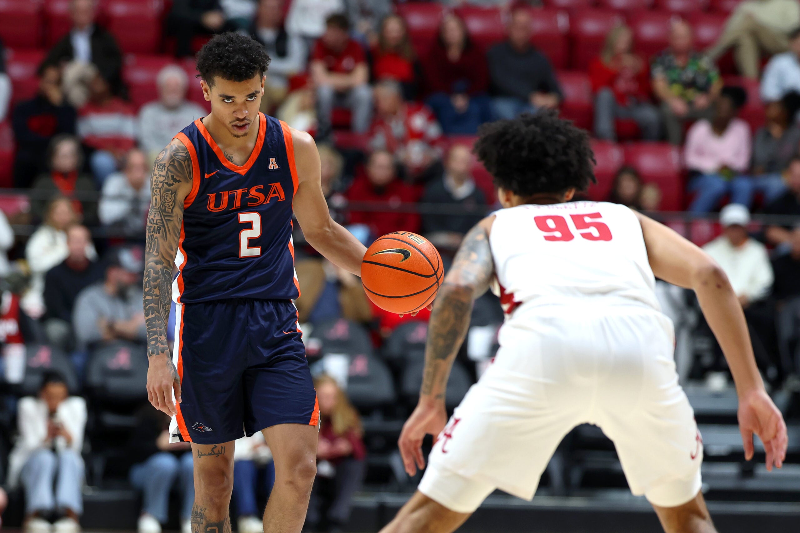 Dec 7, 2025; Tuscaloosa, Alabama, USA; UTSA Roadrunners guard Austin Nunez (2) stares down Alabama Crimson Tide guard Houston Mallette (95) during the first half at Coleman Coliseum. Mandatory Credit: David Leong-Imagn Images