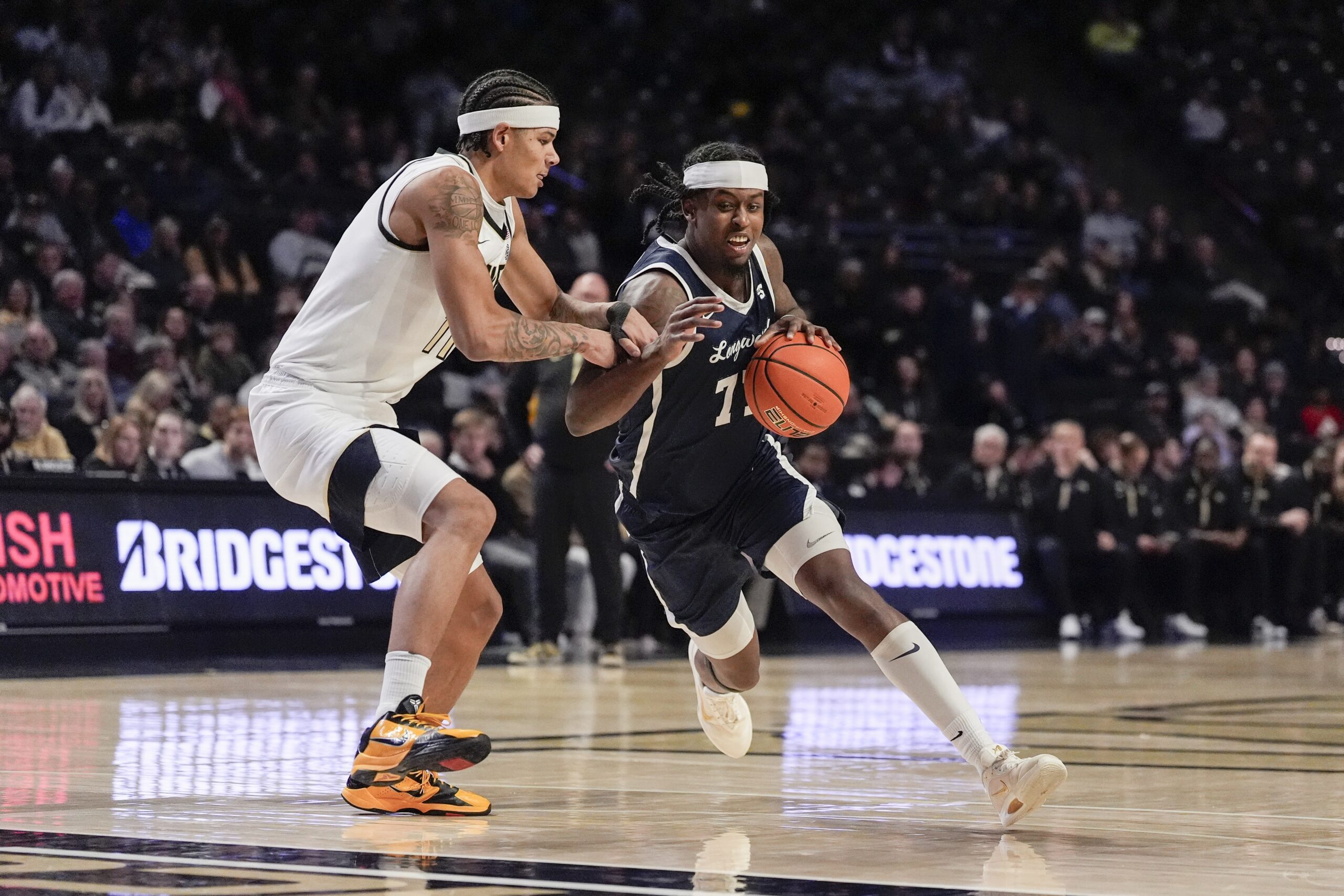Dec 17, 2025; Winston-Salem, North Carolina, USA;  Longwood Lancers forward Elijah Tucker (77) handles the ball against Wake Forest Demon Deacons forward Marqus Marion (11) during the second half at Lawrence Joel Veterans Memorial Coliseum. Mandatory Credit: Jim Dedmon-Imagn Images