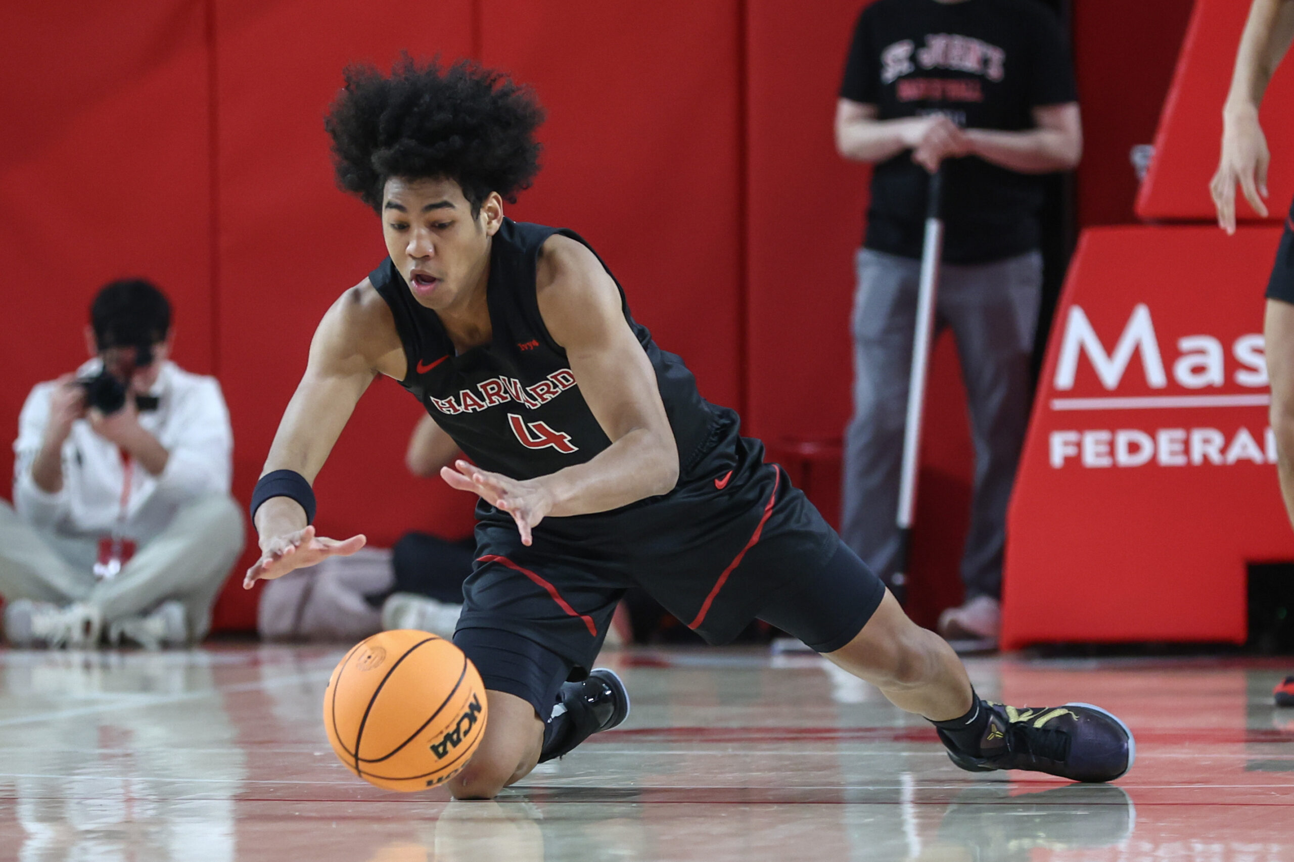 Dec 23, 2025; Queens, New York, USA;  Harvard Crimson guard Robert Hinton (4) dives after a loose ball in the first half against the St. John's Red Storm at Carnesecca Arena. Mandatory Credit: Wendell Cruz-Imagn Images