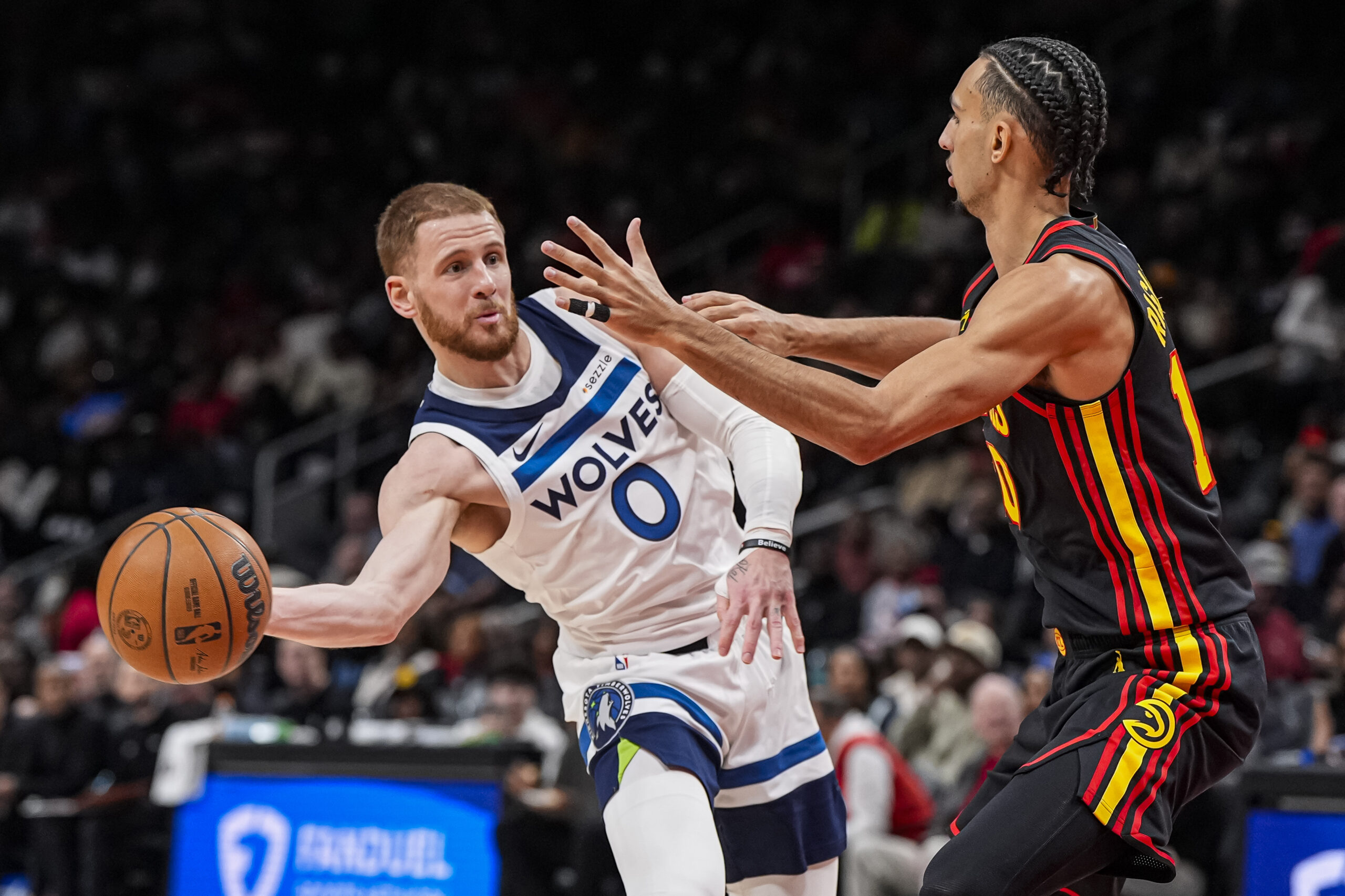 Dec 31, 2025; Atlanta, Georgia, USA; Minnesota Timberwolves guard Donte Divincenzo (0) passes the ball against Atlanta Hawks forward Zaccharie Risacher (10) during the second half at State Farm Arena. Mandatory Credit: Dale Zanine-Imagn Images