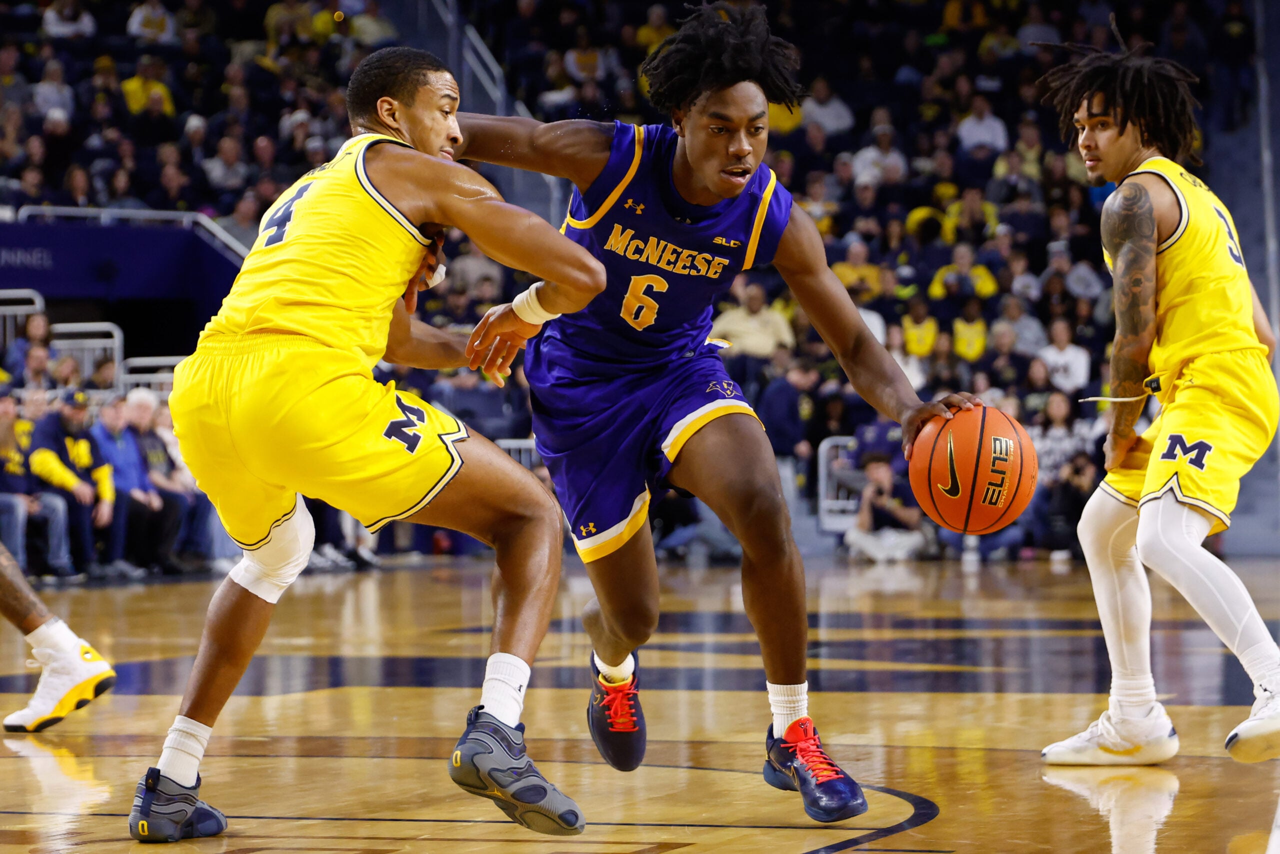 Dec 29, 2025; Ann Arbor, Michigan, USA;  McNeese Cowboys guard Larry Johnson (6) dribbles defended by Michigan Wolverines guard Nimari Burnett (4) at Crisler Center. Mandatory Credit: Rick Osentoski-Imagn Images