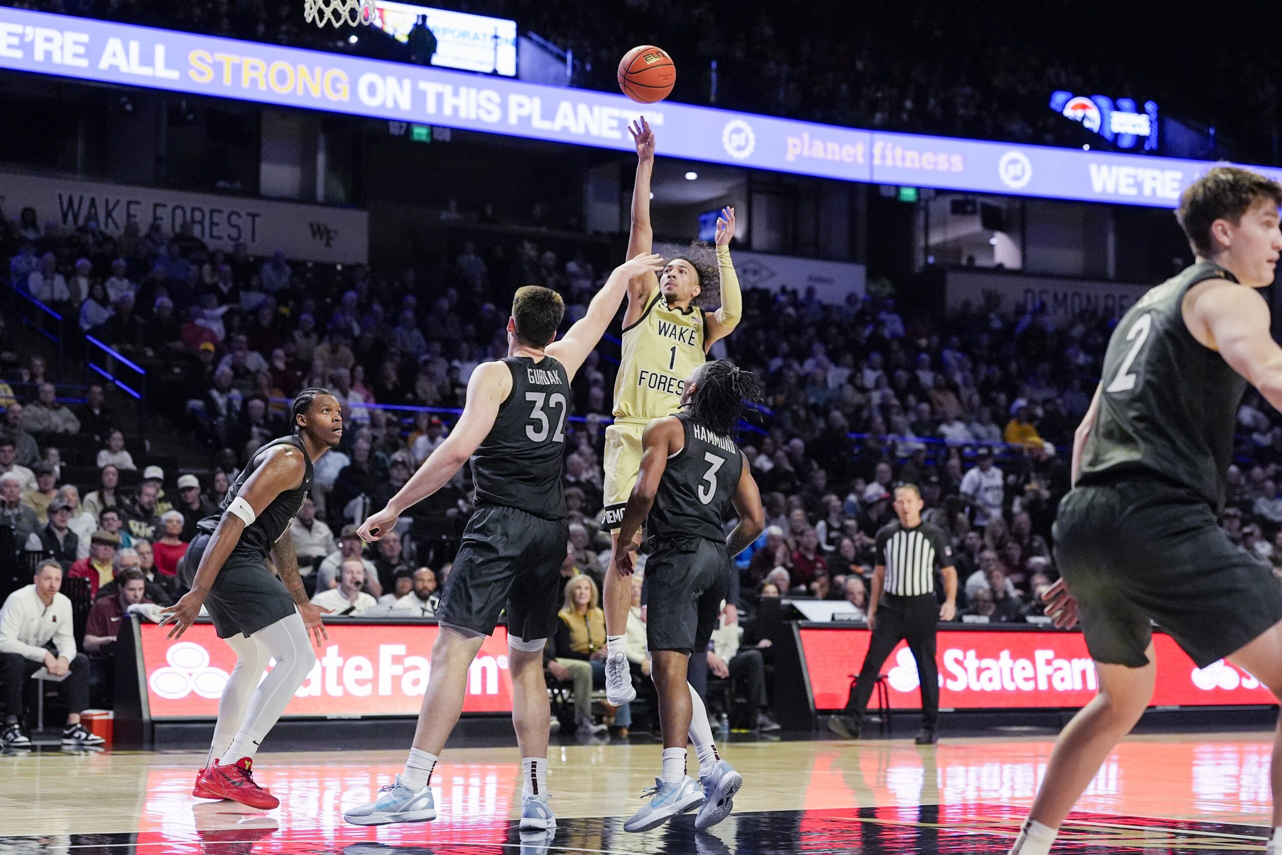 Jan 3, 2026; Winston-Salem, North Carolina, USA; Wake Forest Demon Deacons guard Nate Calmese (1) shoots the ball over Virginia Tech Hokies center Christian Gurdak (32) and guard Ben Hammond (3) during the first half at Lawrence Joel Veterans Memorial Coliseum. Mandatory Credit: Jim Dedmon-Imagn Images