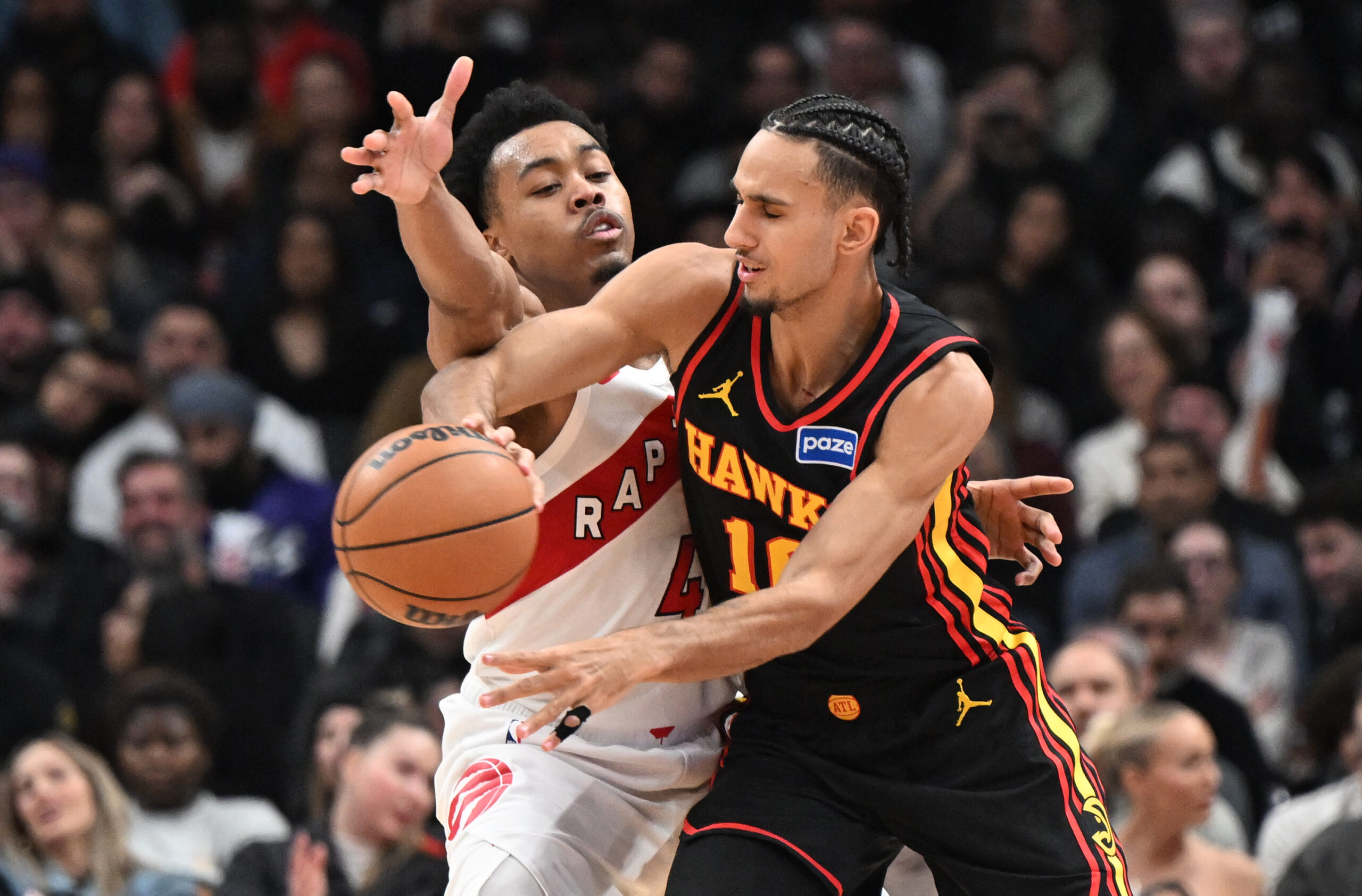 Jan 5, 2026; Toronto, Ontario, CAN;  Atlanta Hawks forward Zaccharie Risacher (10) passes the ball away from Toronto Raptors forward Scottie Barnes (4) in the second half at Scotiabank Arena. Mandatory Credit: Dan Hamilton-Imagn Images
