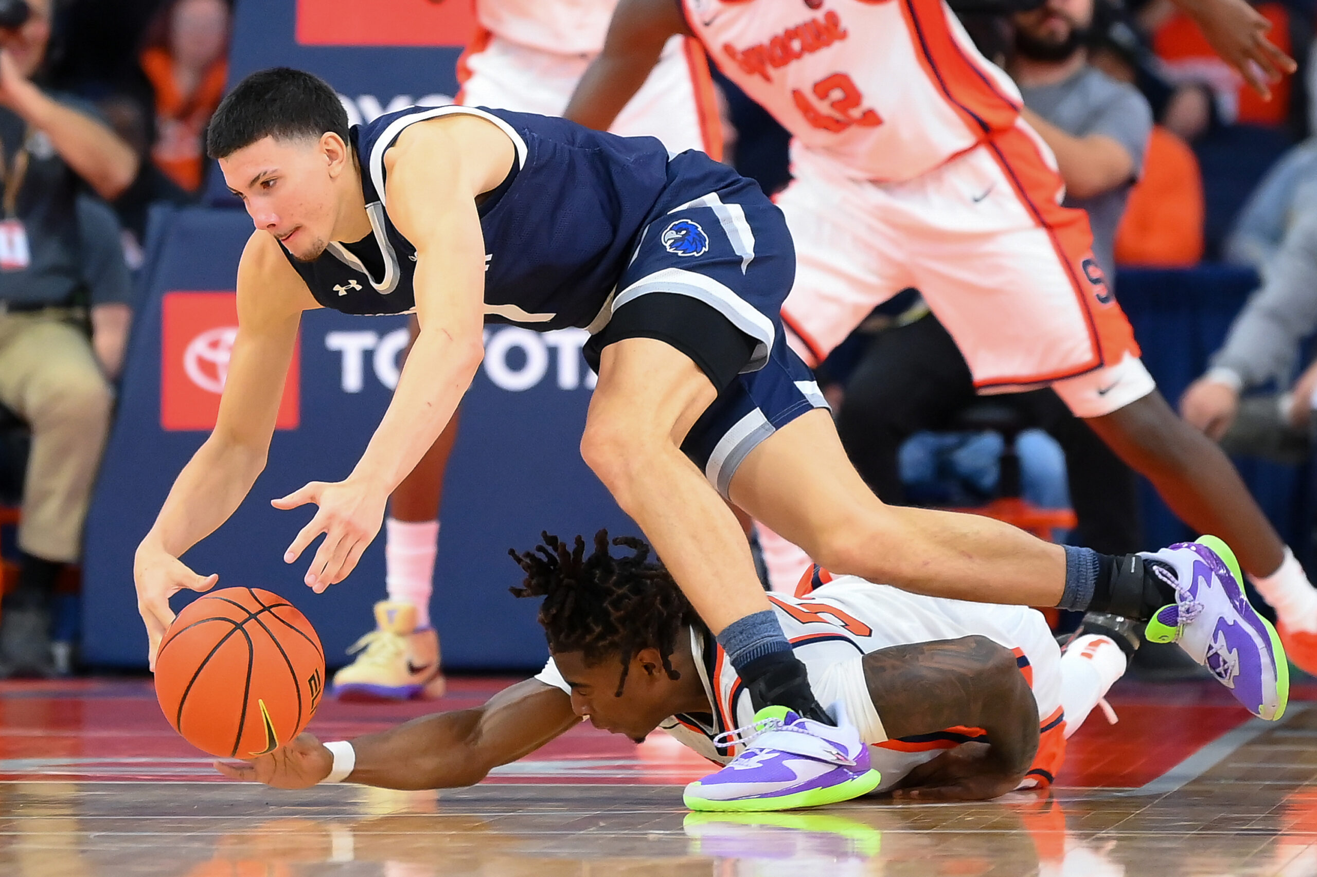 Nov 18, 2025; Syracuse, New York, USA; Monmouth Hawks forward Jason Rivera-Torres (1) and Syracuse Orange guard Bryce Zephir (55) battle for a loose ball during the second half at the JMA Wireless Dome. Mandatory Credit: Rich Barnes-Imagn Images