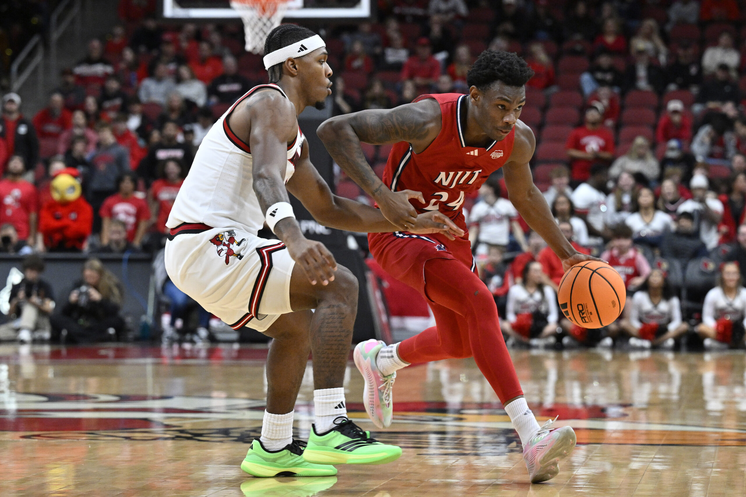Nov 26, 2025; Louisville, Kentucky, USA;  NJIT Highlanders guard Ari Fulton (24) dribbles against Louisville Cardinals guard Ryan Conwell (3) during the first half at KFC Yum! Center. Mandatory Credit: Jamie Rhodes-Imagn Images