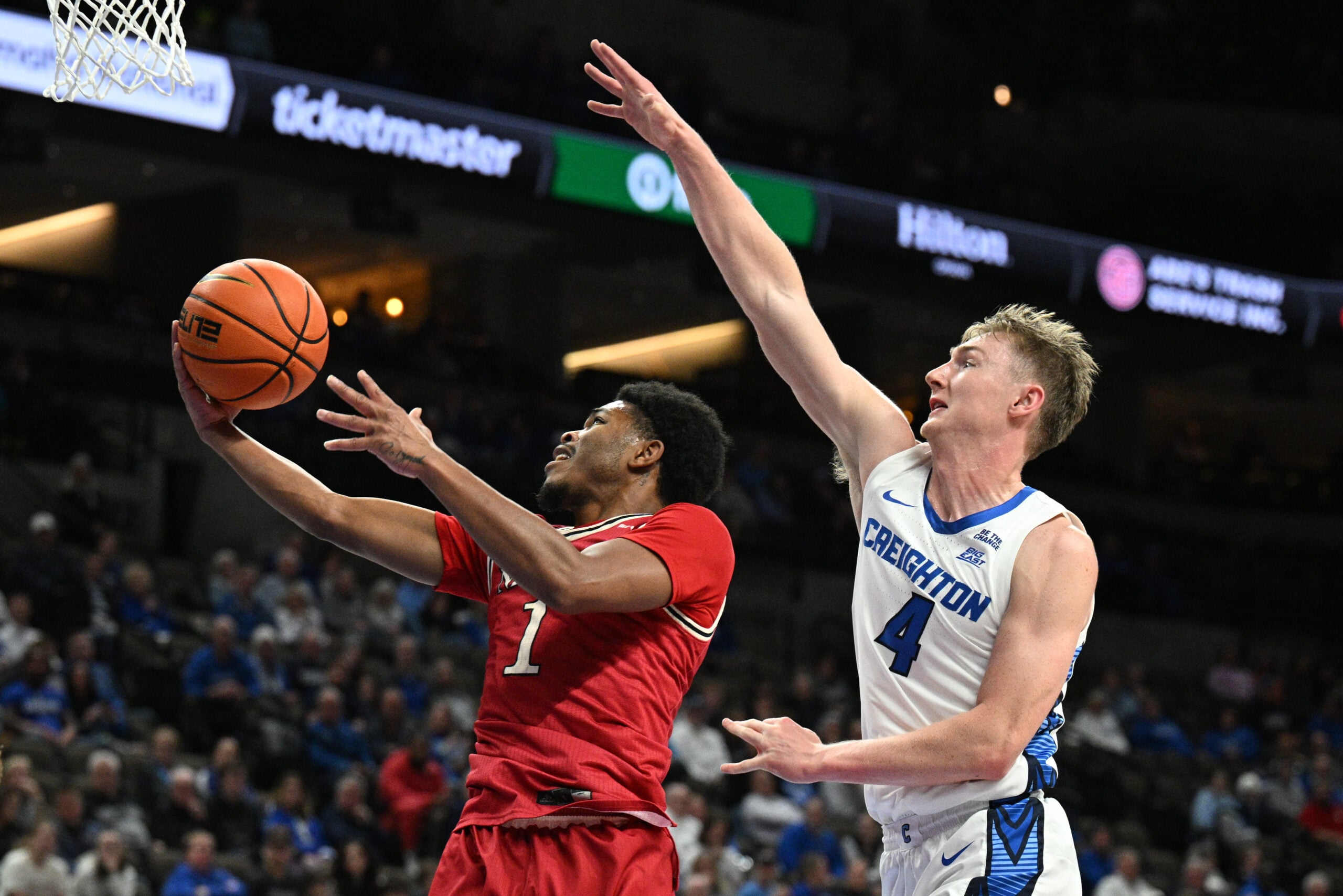 Dec 2, 2025; Omaha, Nebraska, USA; Nicholls State Colonels guard Trae English (1) scores against Creighton Bluejays guard Josh Dix (4) during the first half at CHI Health Center Omaha. Mandatory Credit: Steven Branscombe-Imagn Images