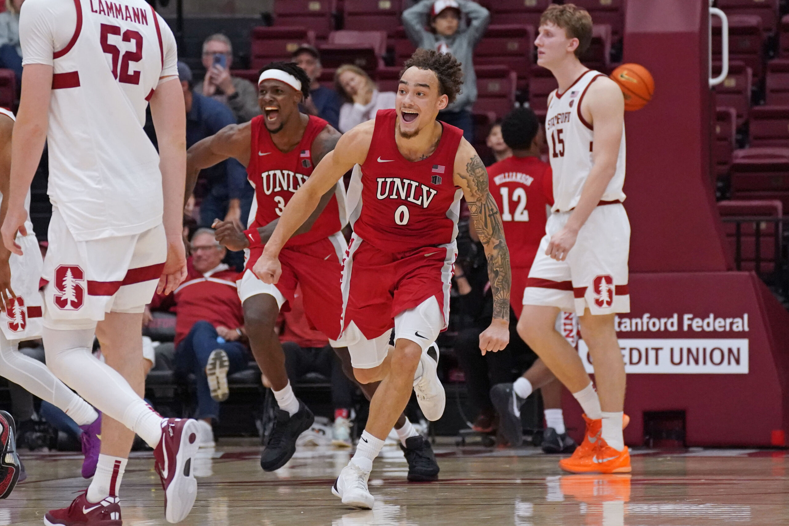 Dec 7, 2025; Stanford, California, USA;  UNLV Runnin' Rebels guard Dra Gibbs-Lawhorn (0) and center Emmanuel Stephen (34) celebrates after the buzzer sounds as Stanford Cardinal forward/center Aidan Cammann (52) and Stanford Cardinal forward/center Oskar Giltay (15) look on in the second half at Maples Pavilion. Mandatory Credit: David Gonzales-Imagn Images
