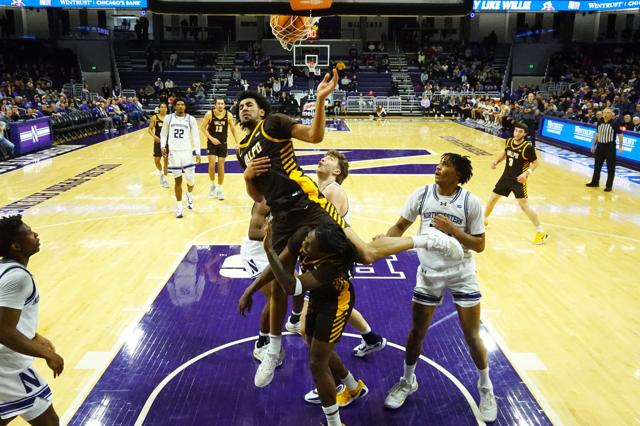 Dec 16, 2025; Evanston, Illinois, USA; Valparaiso Beacons forward JT Pettigrew (7) scores on Northwestern Wildcats forward Nick Martinelli (2) during the second half at Welsh-Ryan Arena. Mandatory Credit: David Banks-Imagn Images
