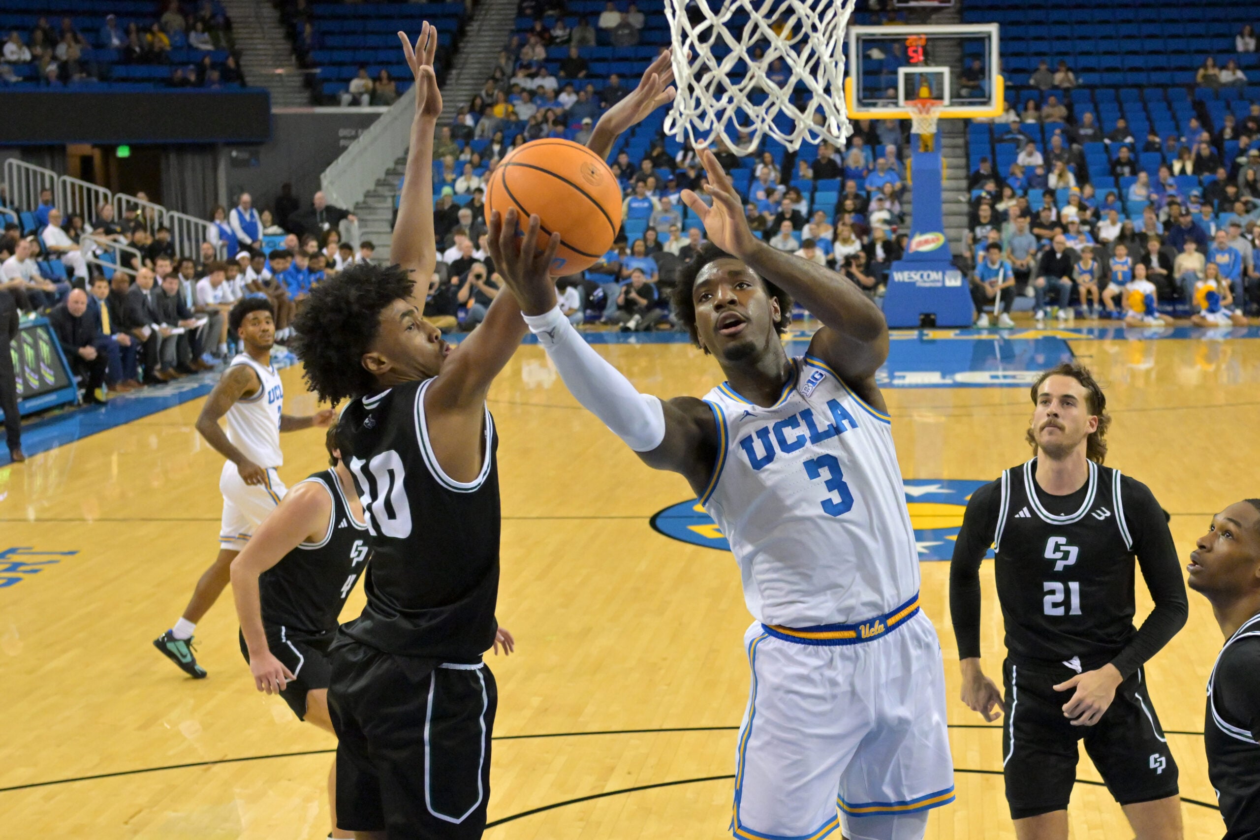 Dec 19, 2025; Los Angeles, California, USA; UCLA Bruins guard Eric Dailey Jr. (3) is defended by Cal Poly Mustangs guard Hamad Mousa (10) as he goes up for a basket during the first half at Pauley Pavilion presented by Wescom Financial. Mandatory Credit: Jayne Kamin-Oncea-Imagn Images