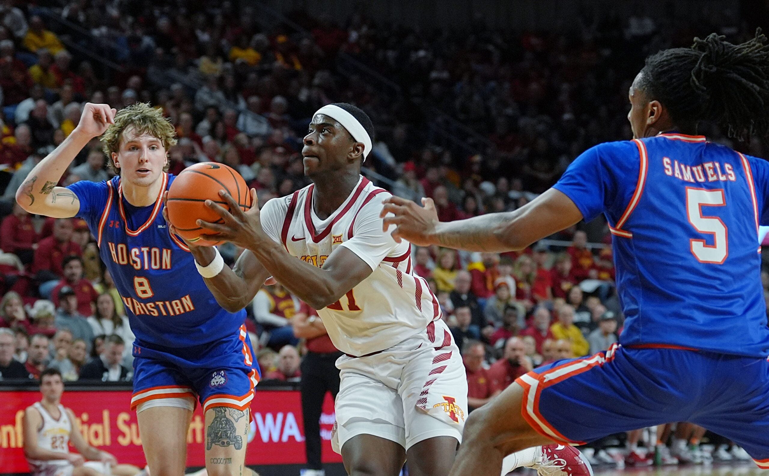 Iowa State Cyclones forward Killyan Toure (27) drives with the ball to the basket between Houston Christian Huskies forward Trent Johnson (8) and guard D'Aundre Samuels (5) during the first half in the NCAA men’s basketball on Dec. 29. 2025, at Hilton Coliseum in Ames, Iowa.