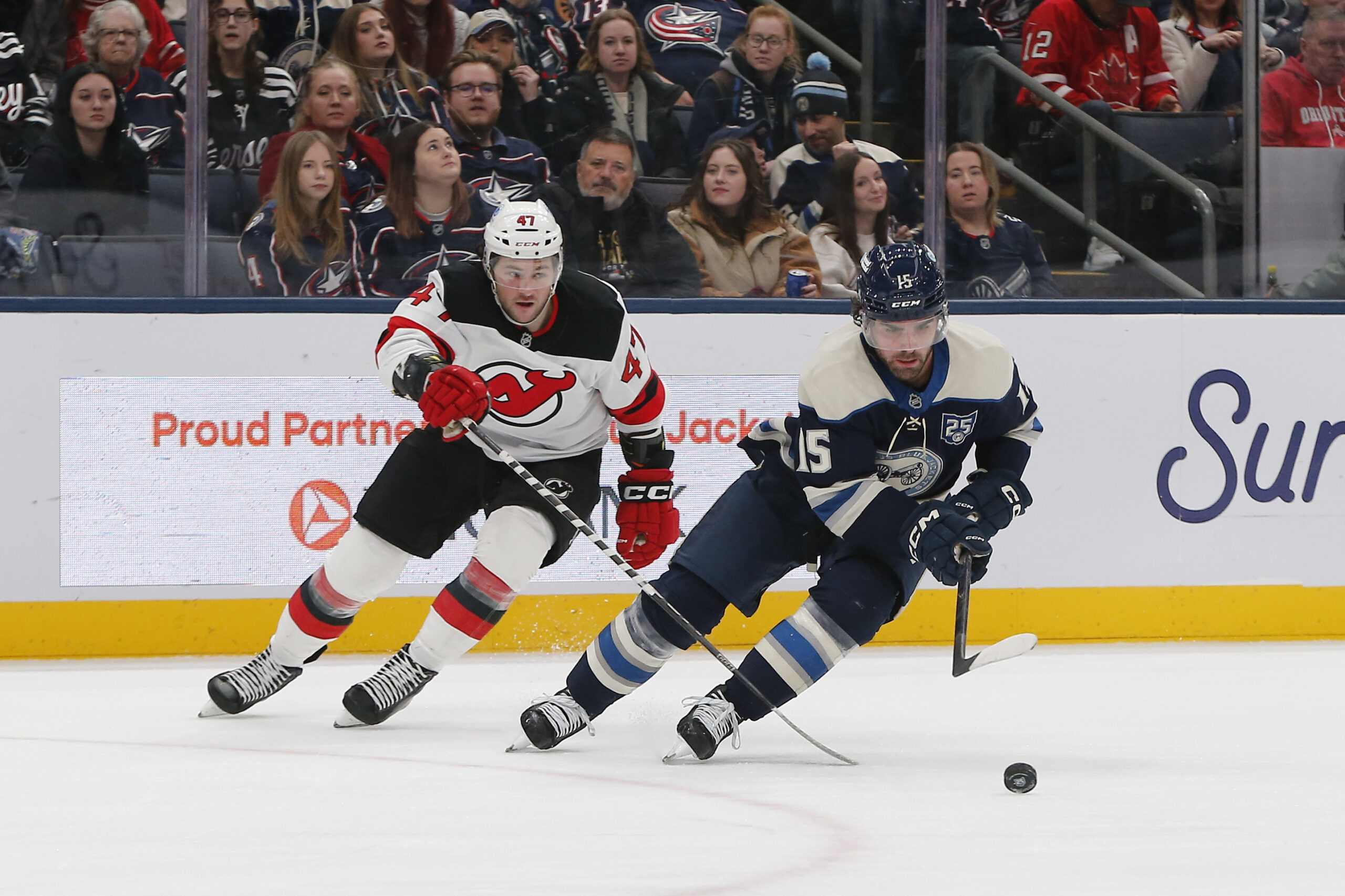 Dec 31, 2025; Columbus, Ohio, USA; Columbus Blue Jackets defenseman Dante Fabbro (15) carries the puck away from New Jersey Devils left wing Paul Cotter (47) during the third period at Nationwide Arena. Mandatory Credit: Russell LaBounty-Imagn Images