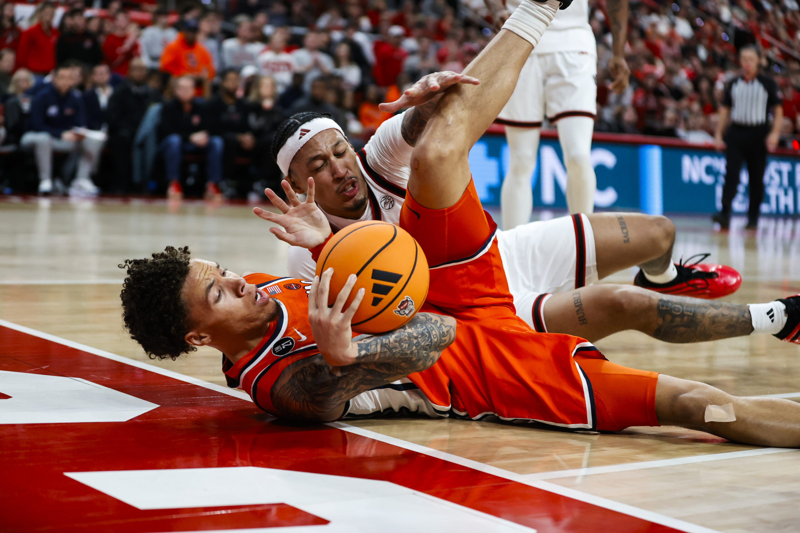Jan 27, 2026; Raleigh, North Carolina, USA; NC State Wolfpack forward Darrion Williams (1) and Syracuse Orange guard Nate Kingz (4) react to the call during the second half of the game at Lenovo Center. Mandatory Credit: Jaylynn Nash-Imagn Images