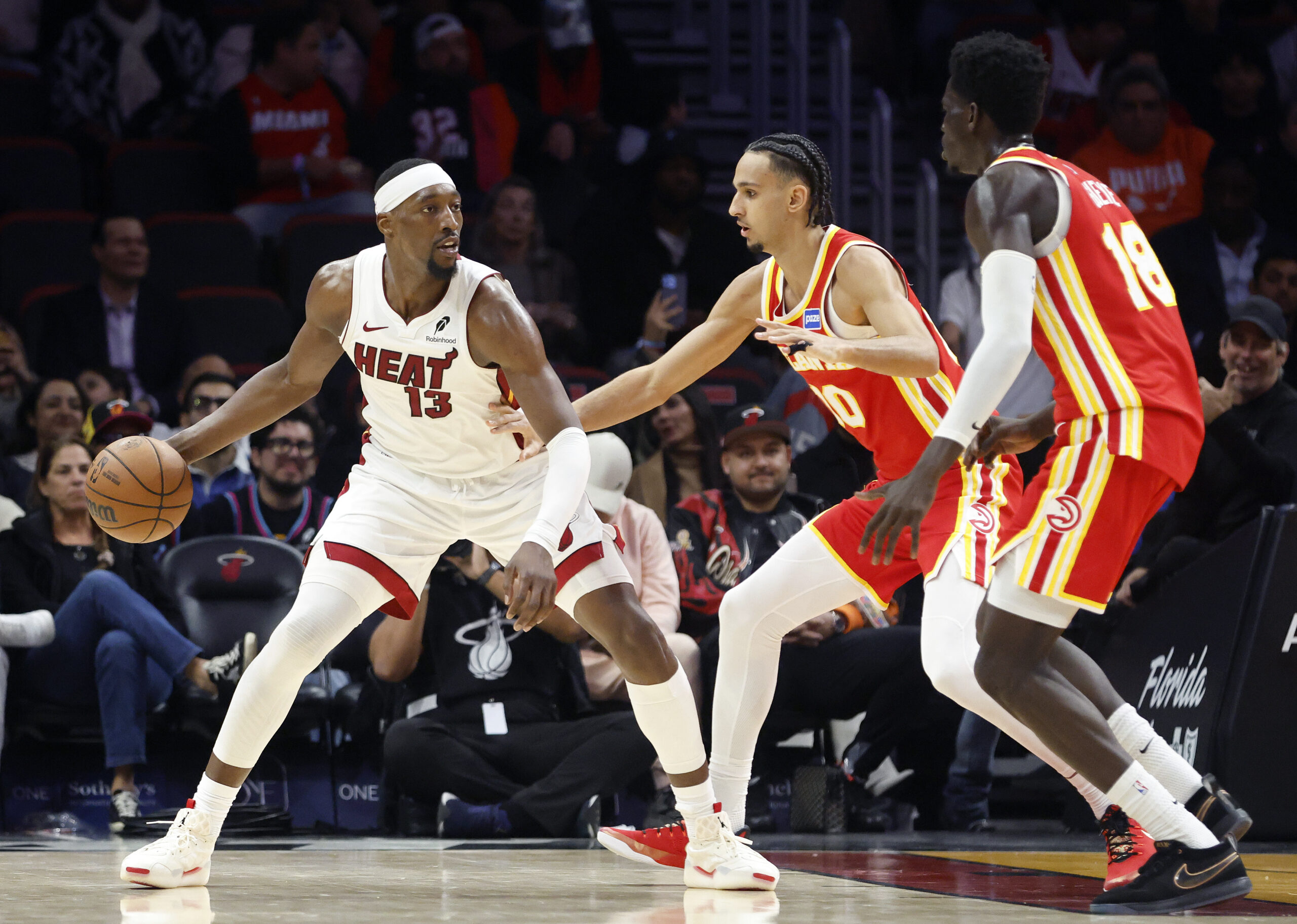 Feb 3, 2026; Miami, Florida, USA; Atlanta Hawks forward Zaccharie Risacher (10) and forward Mouhamed Gueye (18) defend Miami Heat center Bam Adebayo (13) during the second half at Kaseya Center. Mandatory Credit: Rhona Wise-Imagn Images