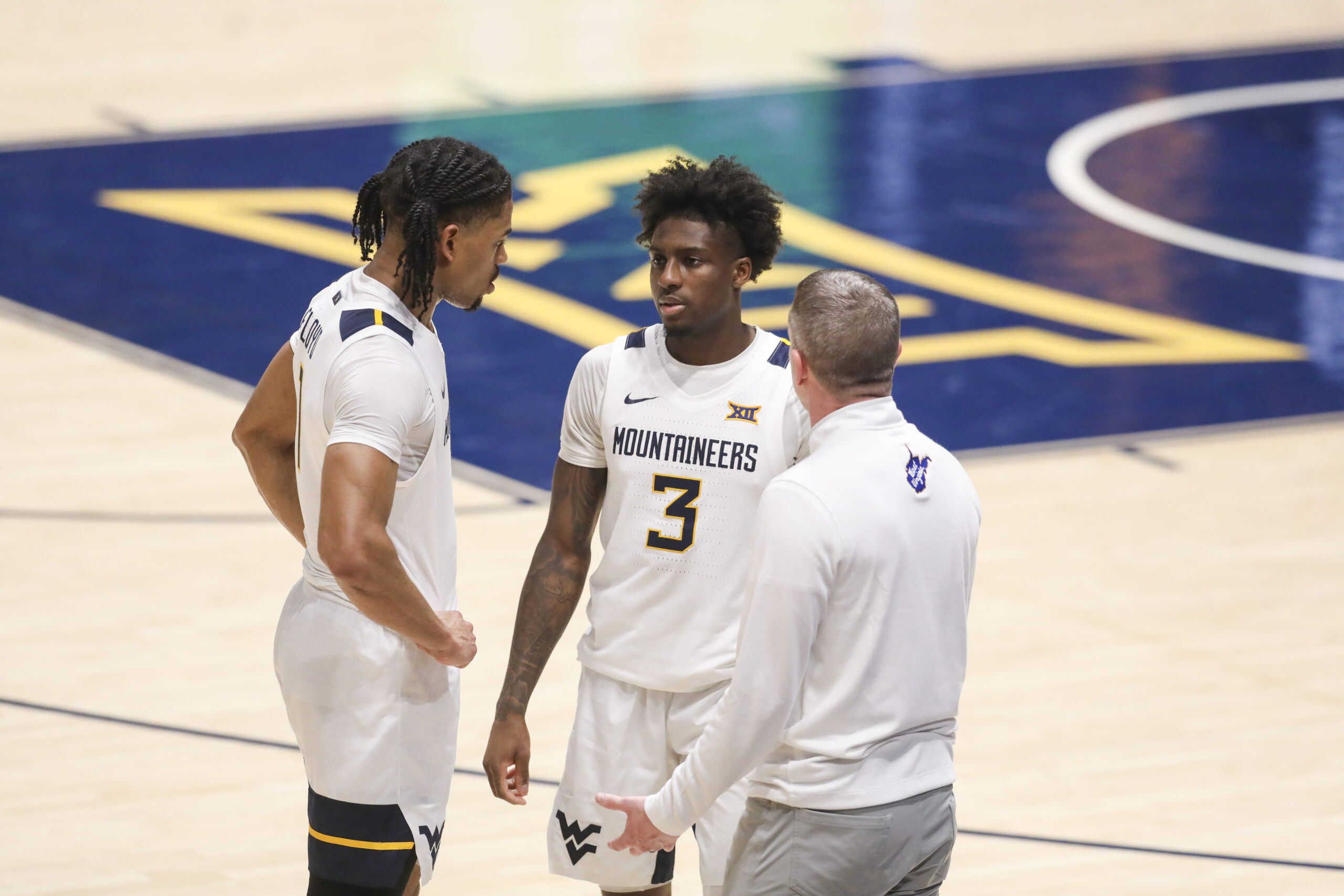 Feb 18, 2026; Morgantown, West Virginia, USA; West Virginia Mountaineers head coach Ross Hodge talks with guard Jasper Floyd (1) and  guard Honor Huff (3) during the second half against the Utah Utes at Hope Coliseum. Mandatory Credit: Ben Queen-Imagn Images