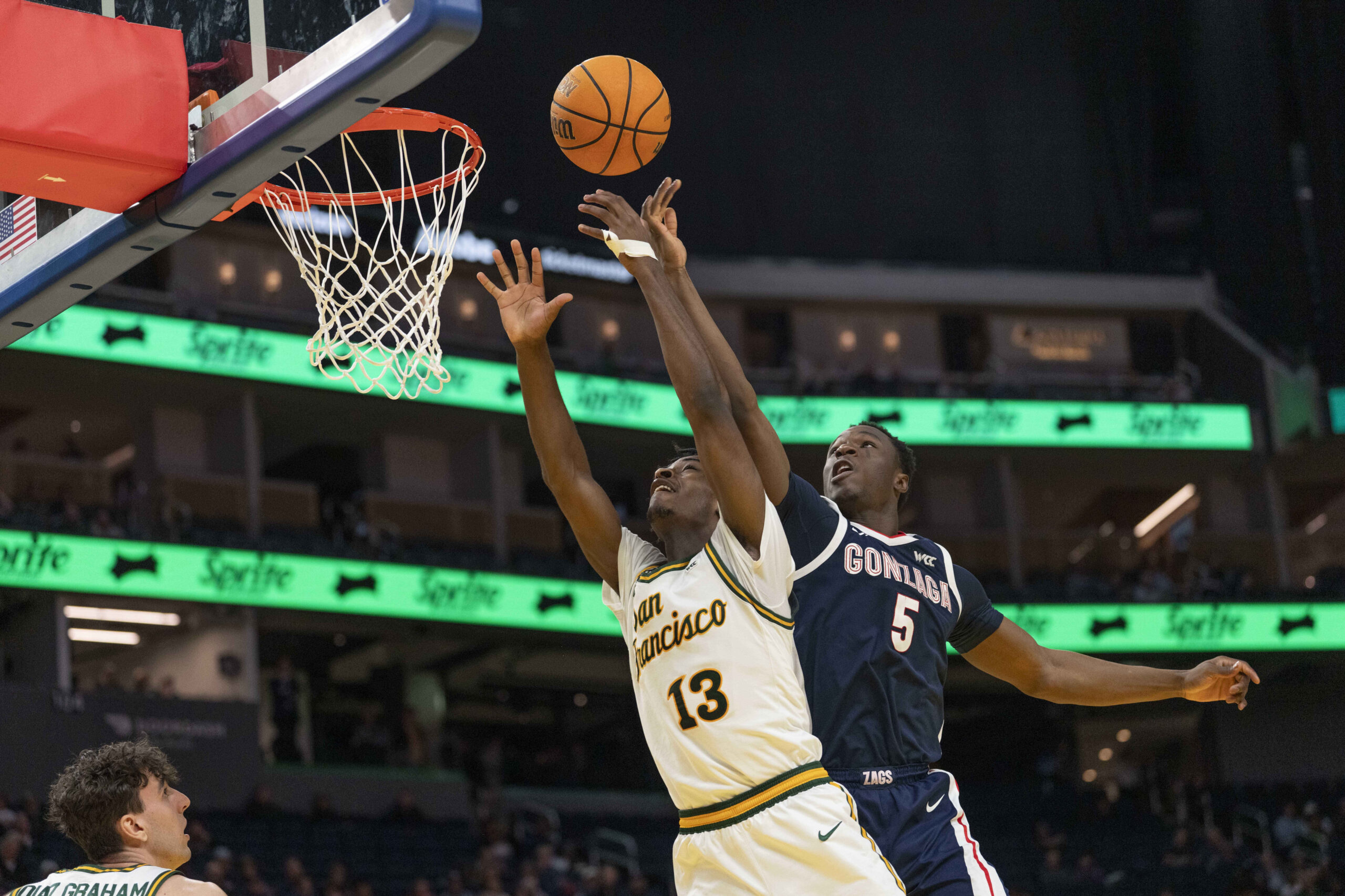 Feb 18, 2026; San Francisco, California, USA;  San Francisco Dons guard Legend Smiley (13) and Gonzaga Bulldogs forward Emmanuel Innocenti (5) reach for the ball during the second half at Chase Center. Mandatory Credit: Stan Szeto-Imagn Images