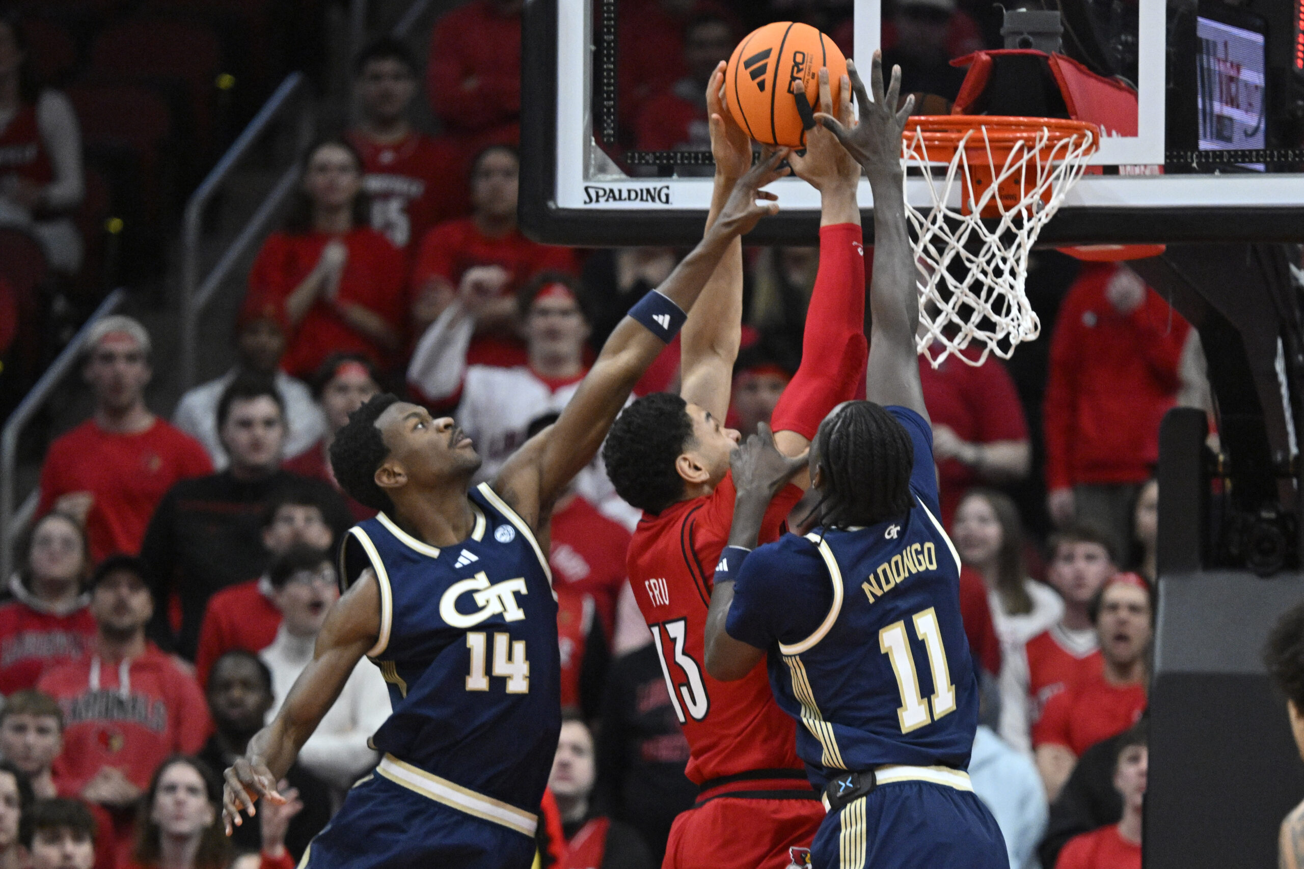 Feb 21, 2026; Louisville, Kentucky, USA; Louisville Cardinals forward Sananda Fru (13) shoots against Georgia Tech Yellow Jackets forward Kowacie Reeves Jr. (14) and forward Baye Ndongo (11) during the first half at KFC Yum! Center. Mandatory Credit: Jamie Rhodes-Imagn Images