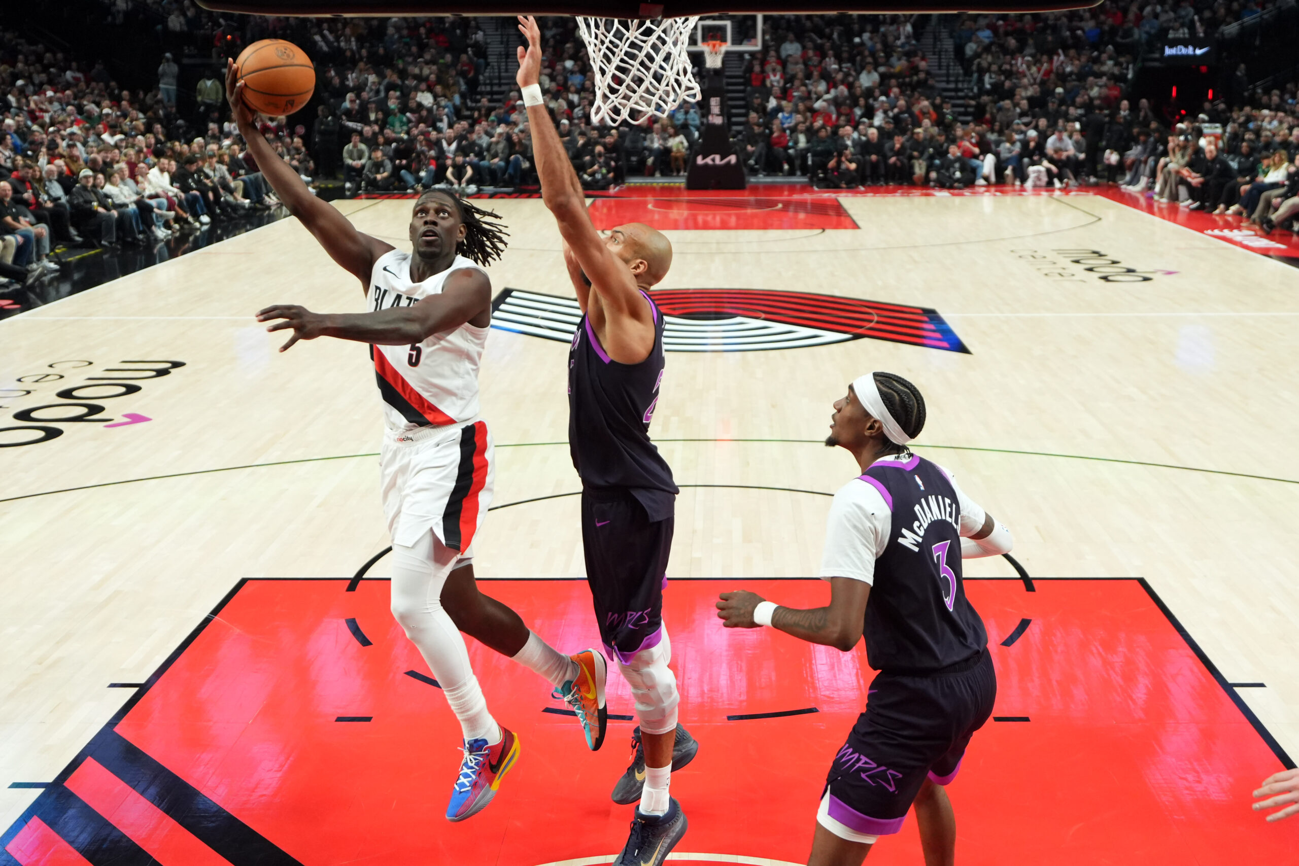 Feb 24, 2026; Portland, Oregon, USA; Portland Trail Blazers guard Jrue Holiday (5) lays up a shot defended by Minnesota Timberwolves center Rudy Gobert (27) during the first half at Moda Center. Mandatory Credit: Soobum Im-Imagn Images