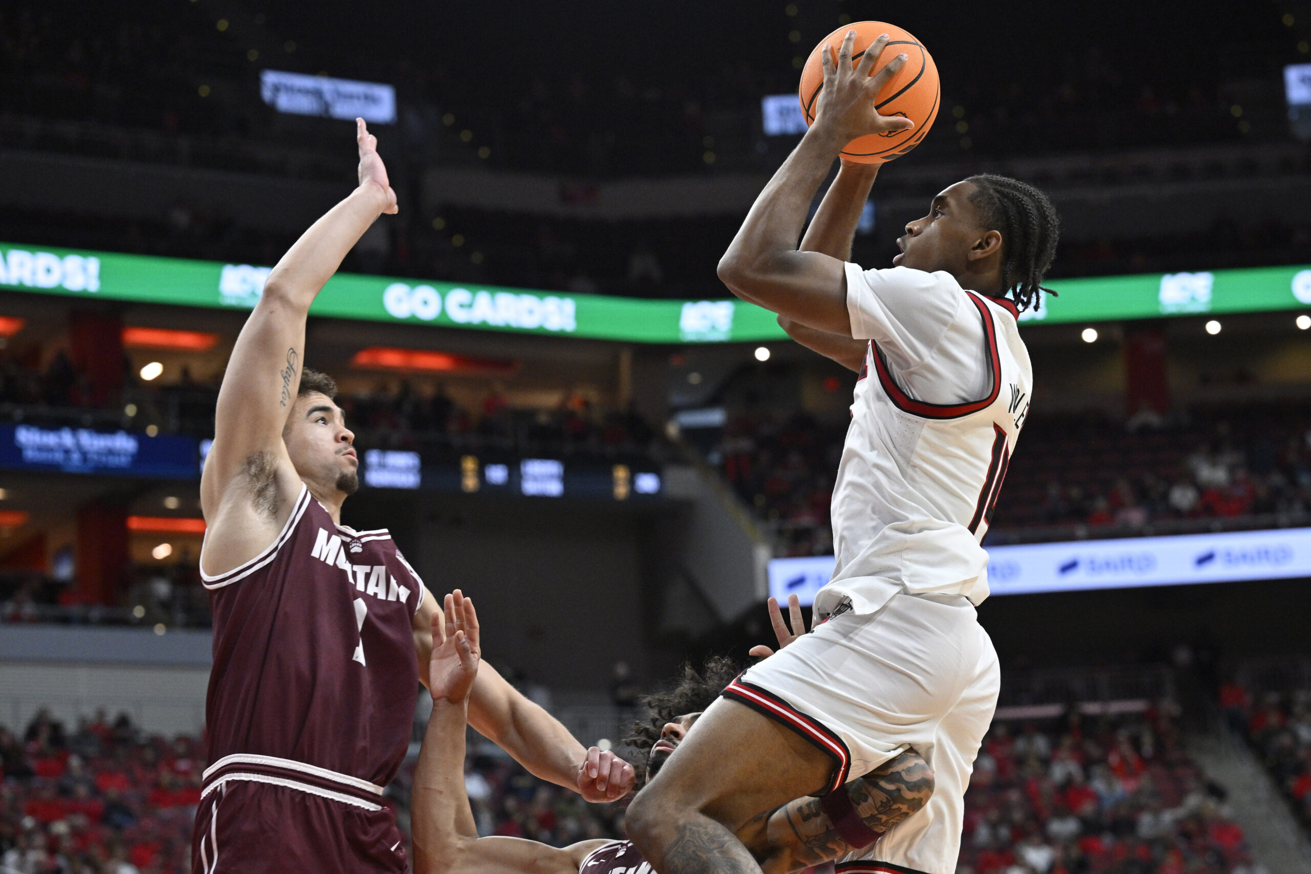 Dec 20, 2025; Louisville, Kentucky, USA;  Louisville Cardinals guard Adrian Wooley (14) shoots against Montana Grizzlies forward Trae Taylor (1) and guard Brooklyn Hicks (3) during the second half at KFC Yum! Center. Louisville defeated Montana 94-54. Mandatory Credit: Jamie Rhodes-Imagn Images