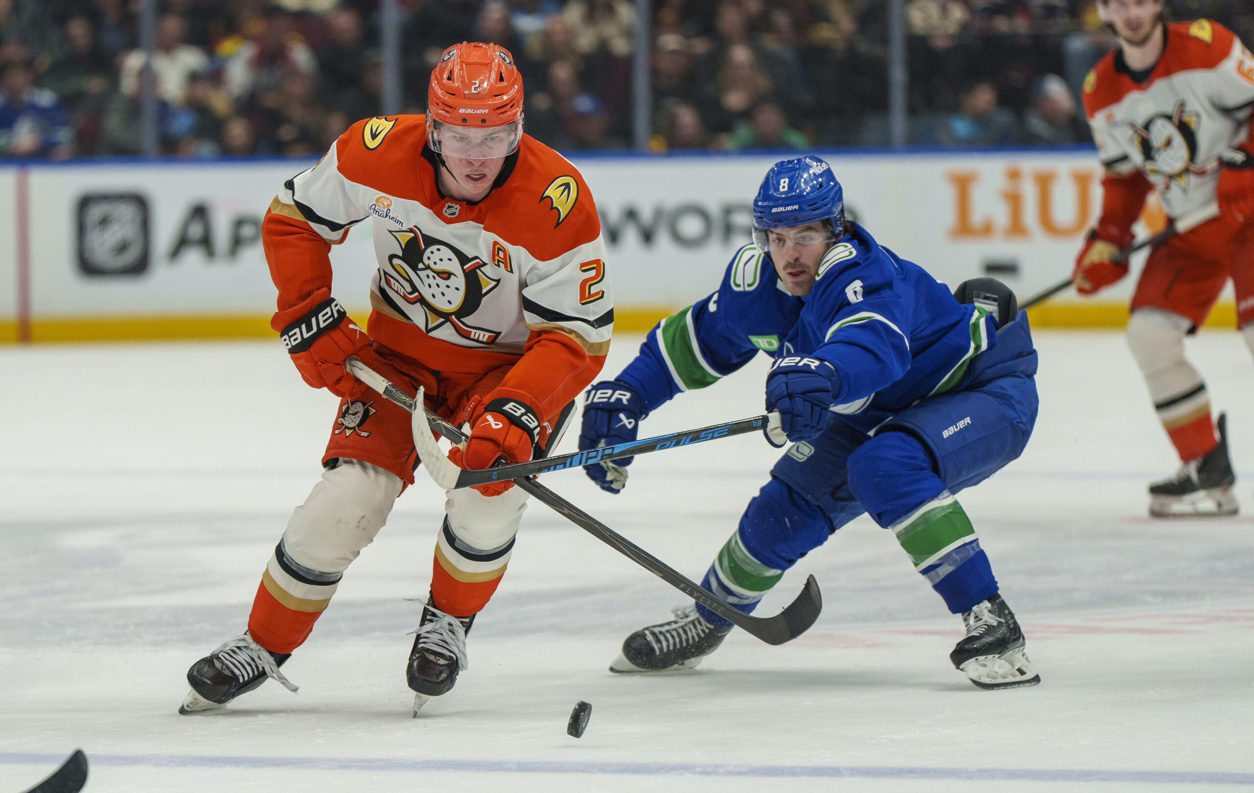 Jan 29, 2026; Vancouver, British Columbia, CAN;  Anaheim Ducks Defenseman Jackson LaCombe (2) chases the puck with Vancouver Canucks left wing Conor Garland (8) in the second period at Rogers Arena. Mandatory Credit: Christopher Morris-Imagn Images