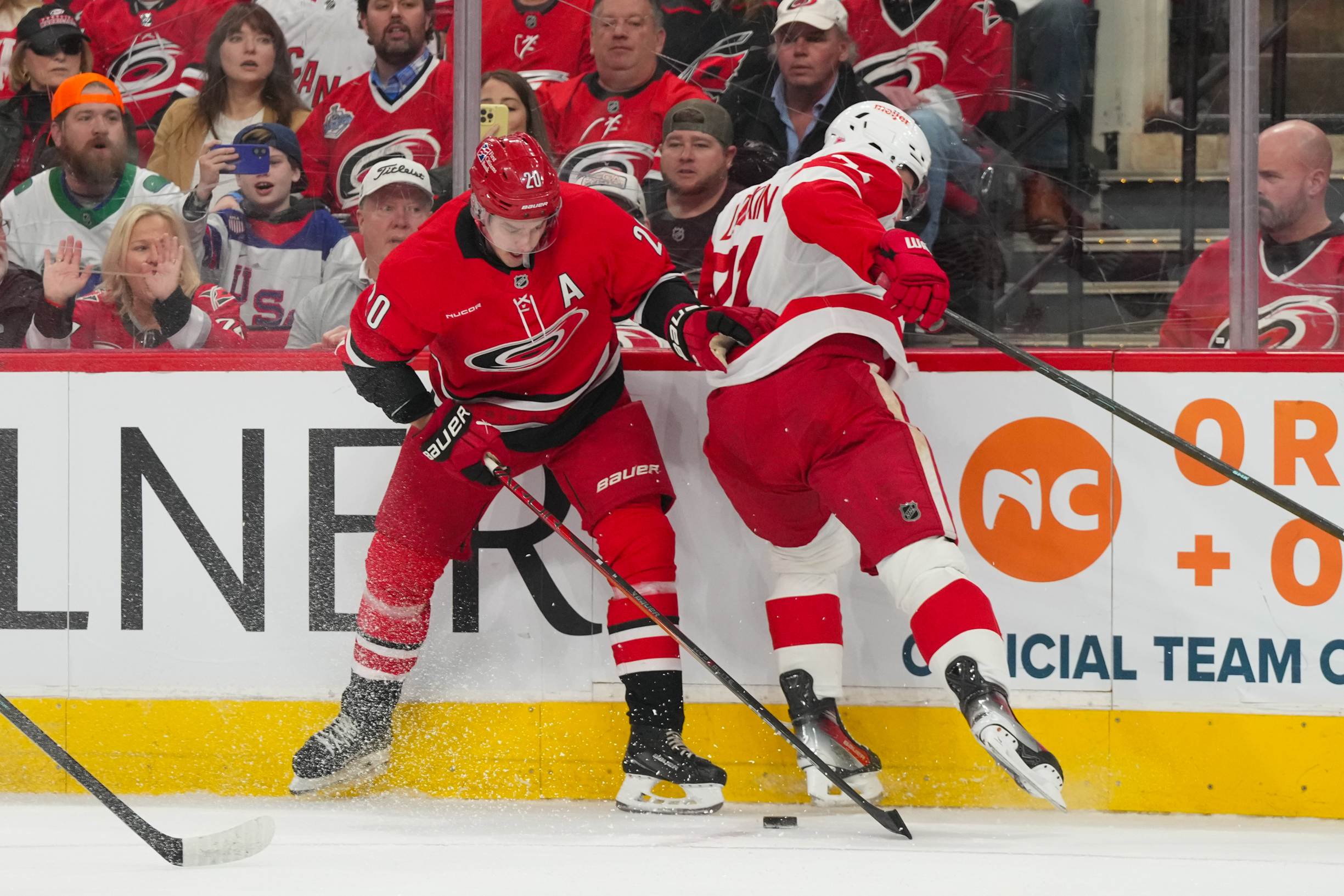 Feb 28, 2026; Raleigh, North Carolina, USA;  Carolina Hurricanes center Sebastian Aho (20) and Detroit Red Wings center Dylan Larkin (71) battle over the puck during the first period at Lenovo Center. Mandatory Credit: James Guillory-Imagn Images