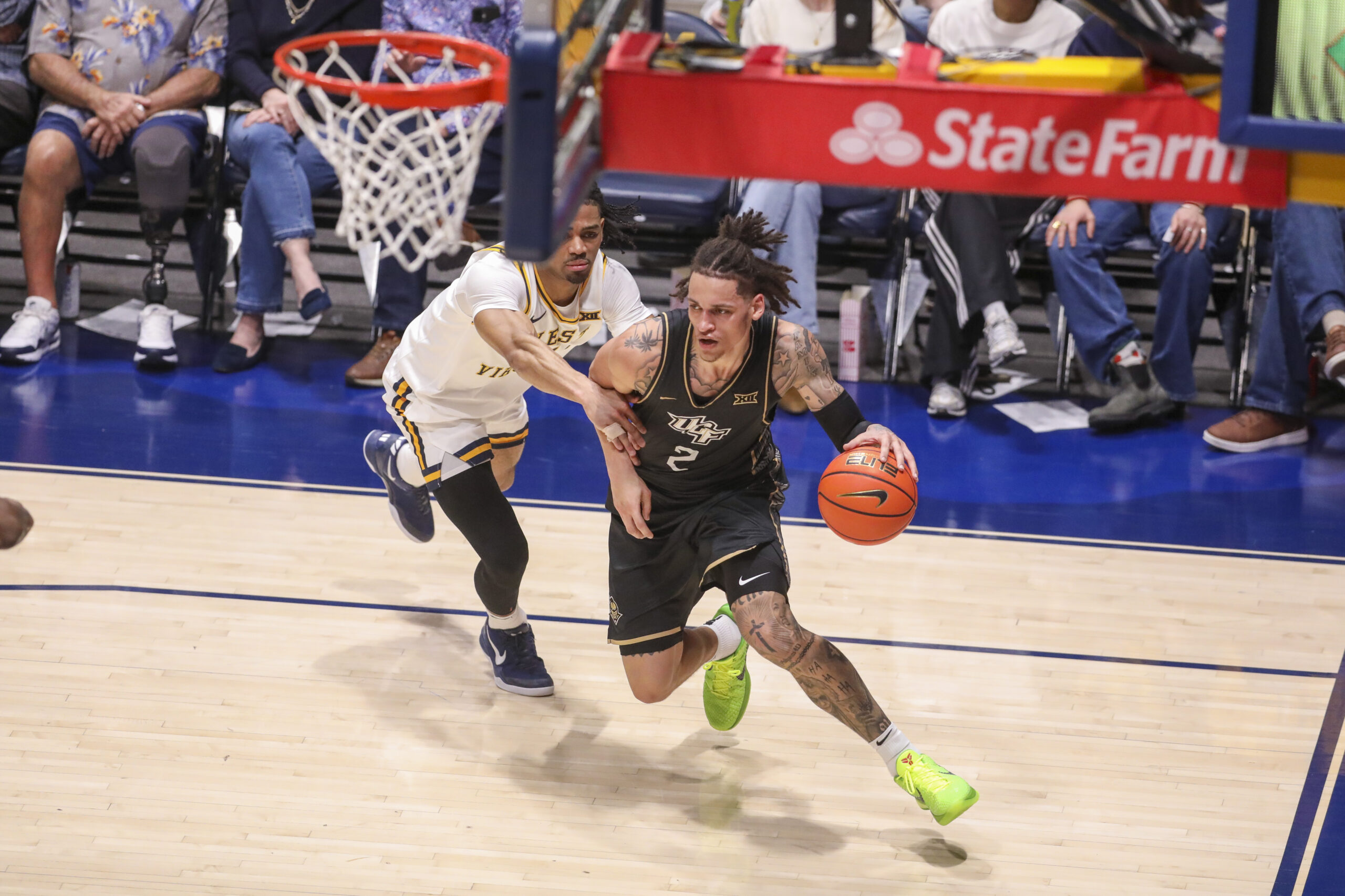 Mar 6, 2026; Morgantown, West Virginia, USA; UCF Knights guard Riley Kugel (2) dribbles along the baseline past West Virginia Mountaineers guard Jasper Floyd (1) during the first half at Hope Coliseum. Mandatory Credit: Ben Queen-Imagn Images