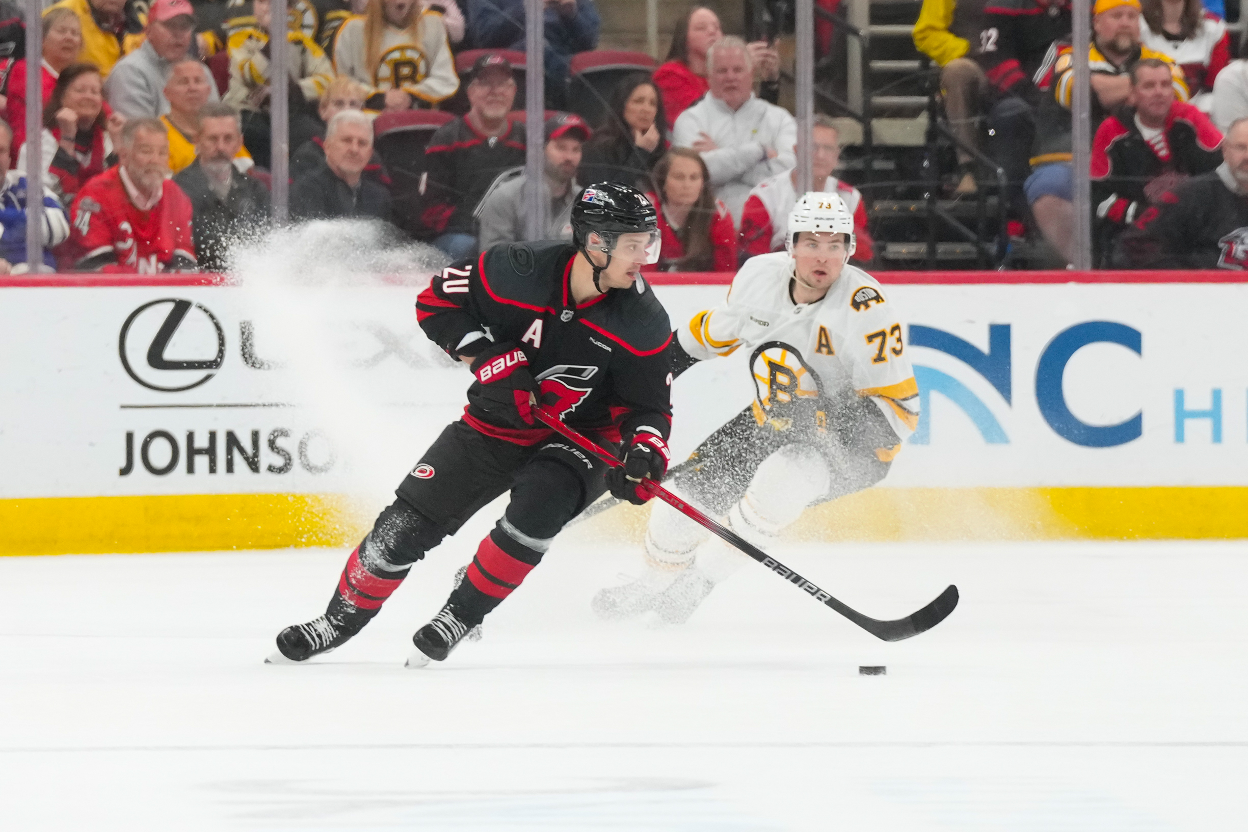 Apr 7, 2026; Raleigh, North Carolina, USA;  Carolina Hurricanes center Sebastian Aho (20) skates with the puck against Boston Bruins defenseman Charlie McAvoy (73) during the third period at Lenovo Center. Mandatory Credit: James Guillory-Imagn Images